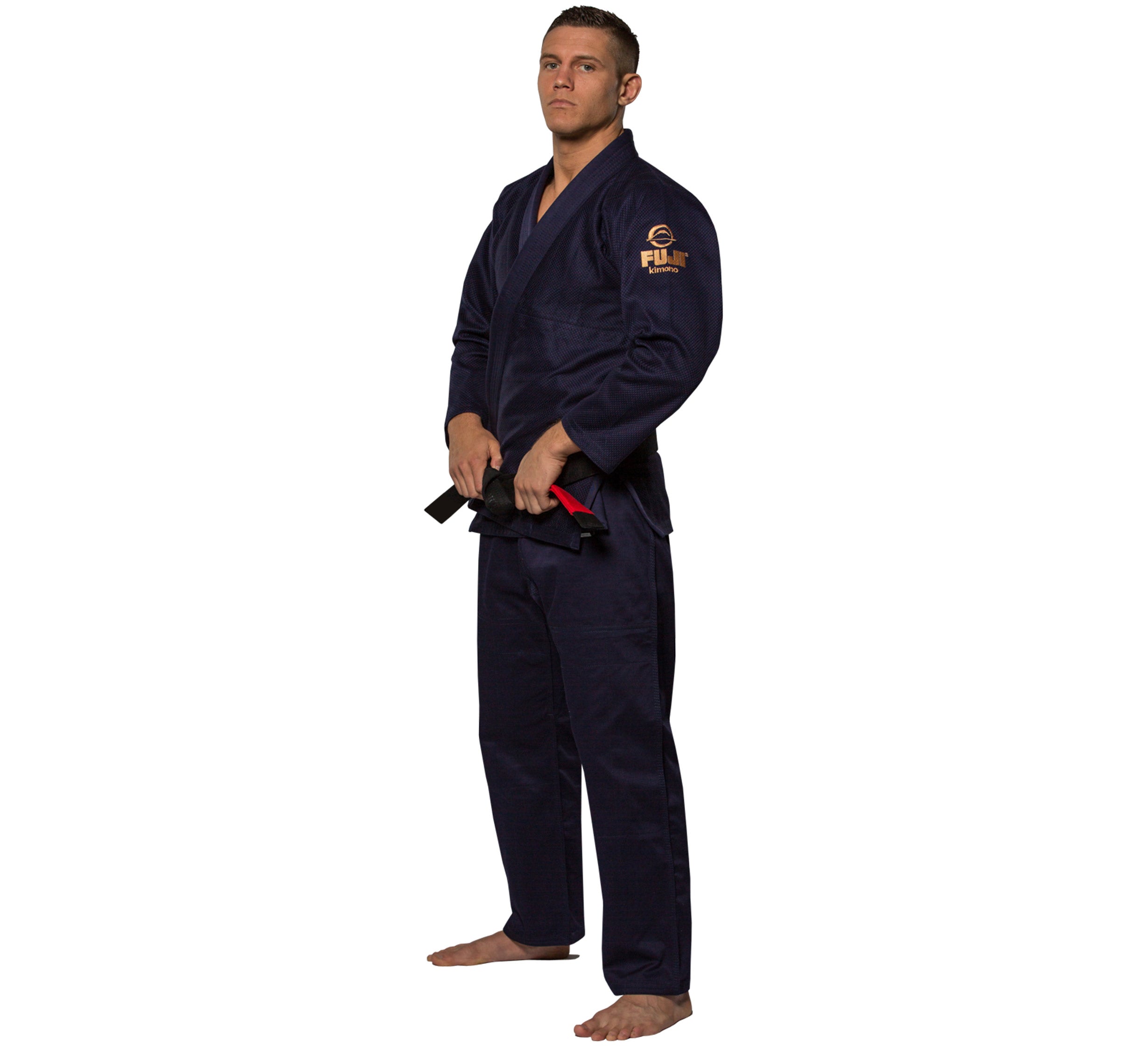 Wearing the All Around BJJ Gi in navy blue, a barefoot individual stands against a white background, holding a black belt with both hands and looking focused while facing slightly to the left.