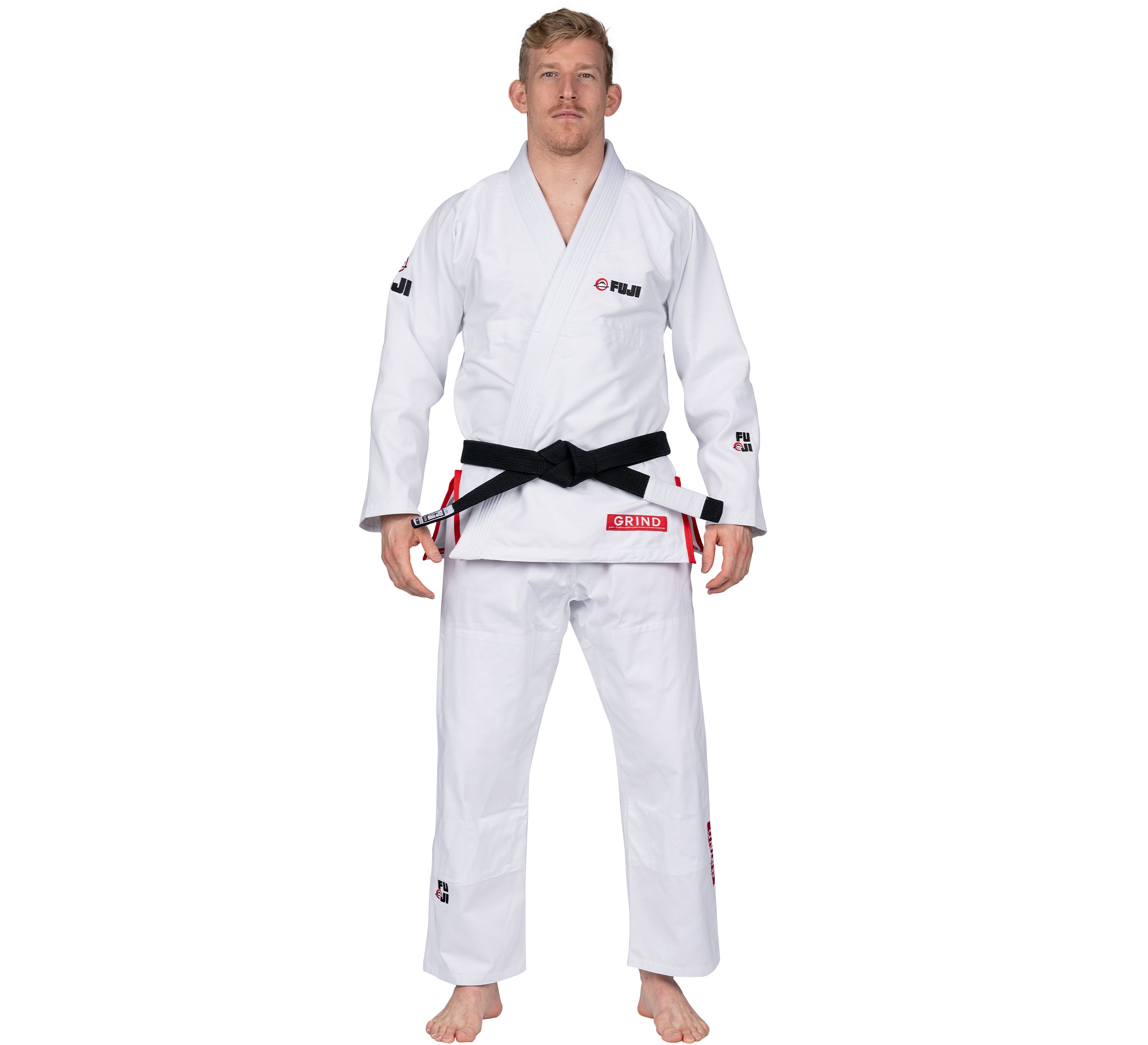 A man wears the Elemental BJJ Gi Grind White with a black belt, standing barefoot against a white background, facing forward with his arms relaxed at his sides.
