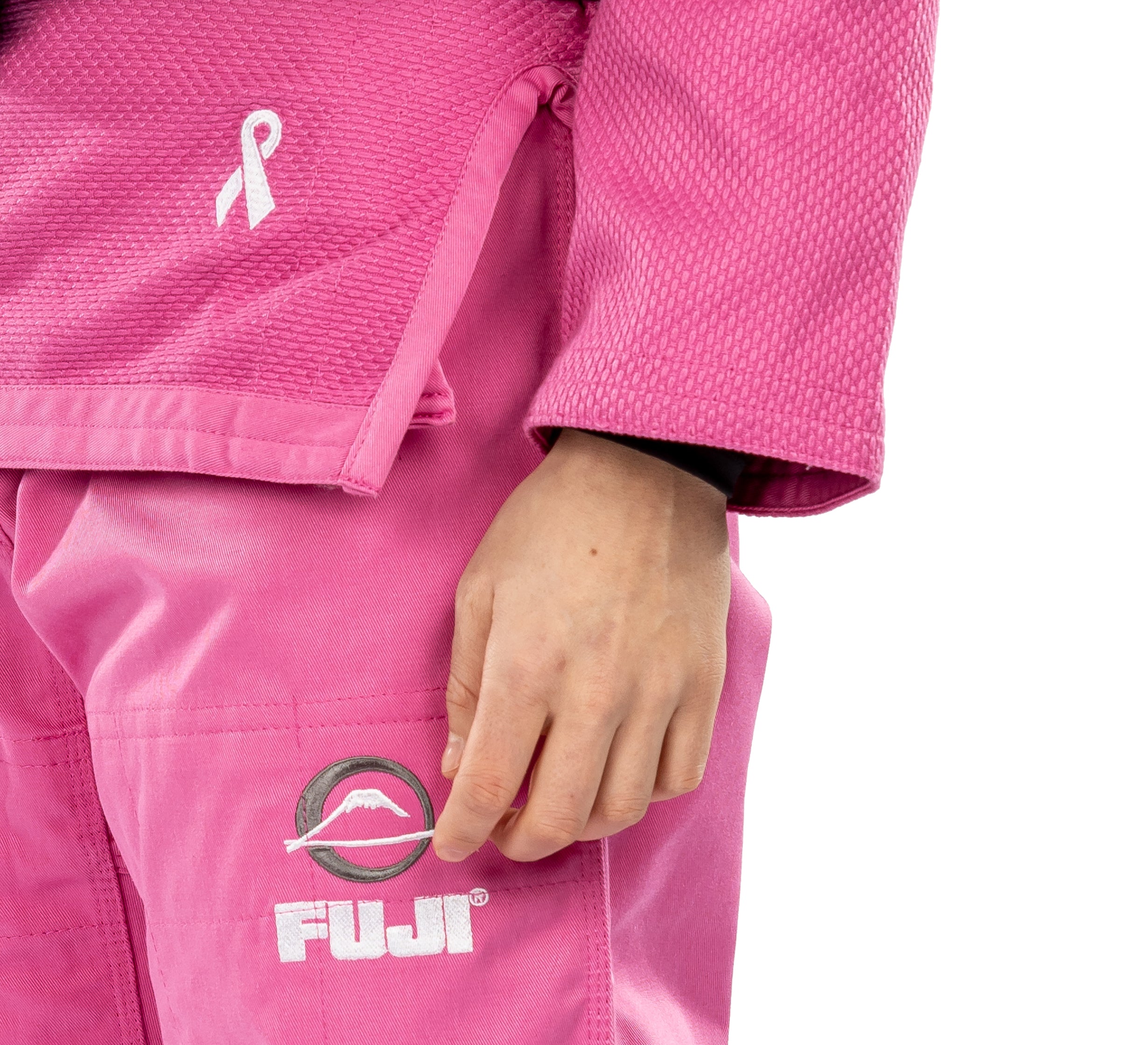 A person wearing the All Around Womens BJJ Gi Pink, featuring a breast cancer awareness ribbon and FUJI logo. Only the lower arm and hand are visible.