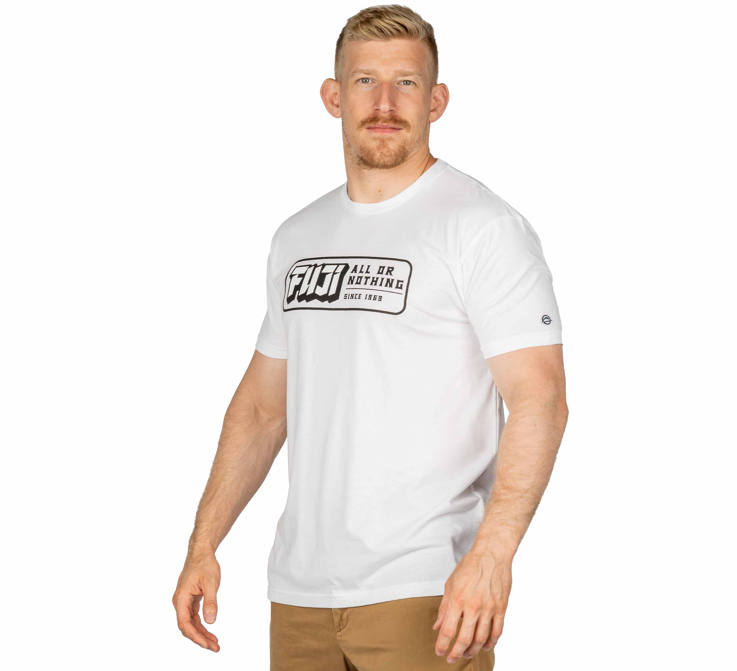 A man with short blond hair and a beard wears a Ranked Jiu-Jitsu White T-Shirt and brown pants, standing against a white background and looking at the camera.
