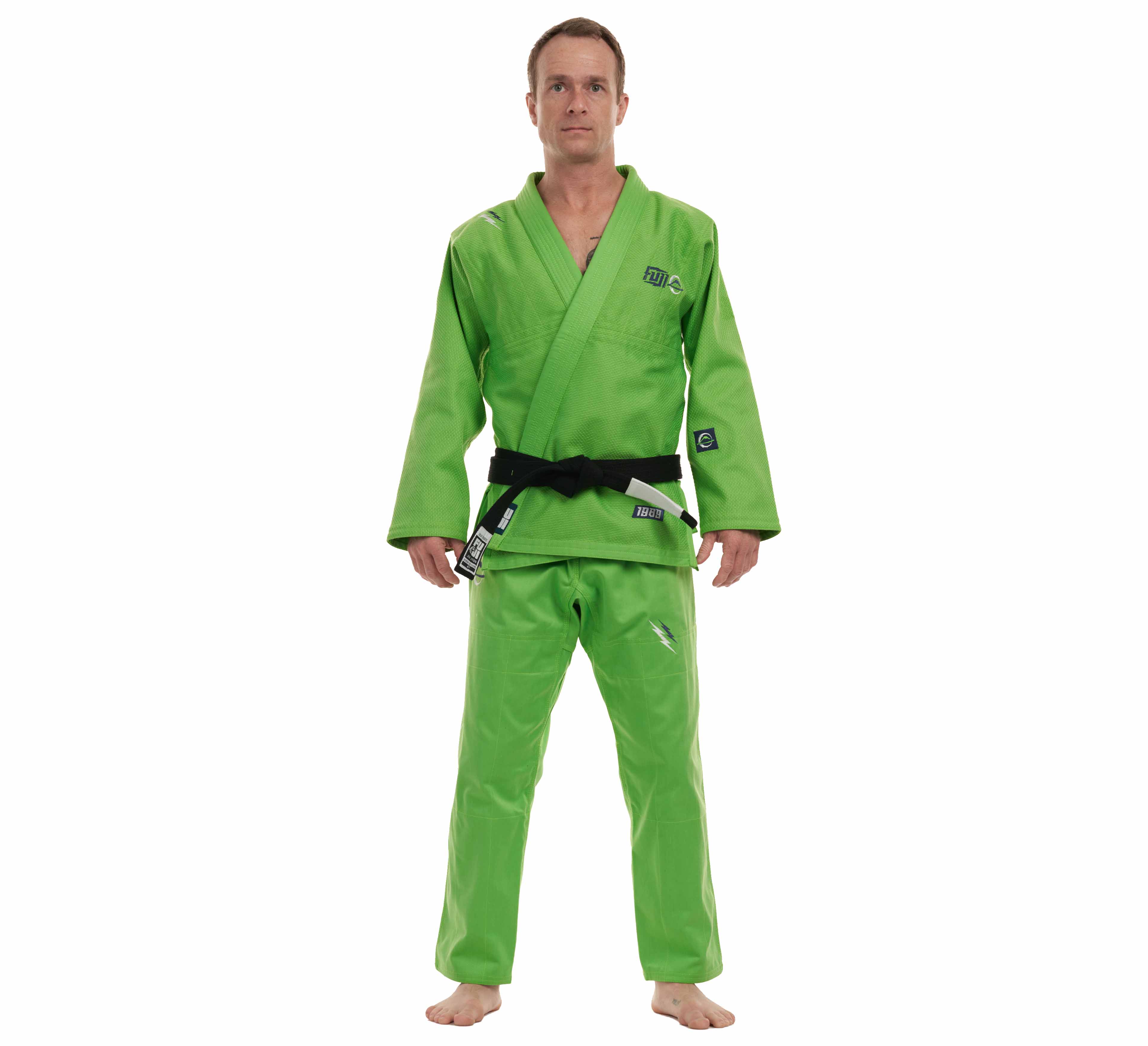 A man stands barefoot against a white background, wearing the All Around BJJ Gi Electric Green Edition with a black belt tied at his waist.