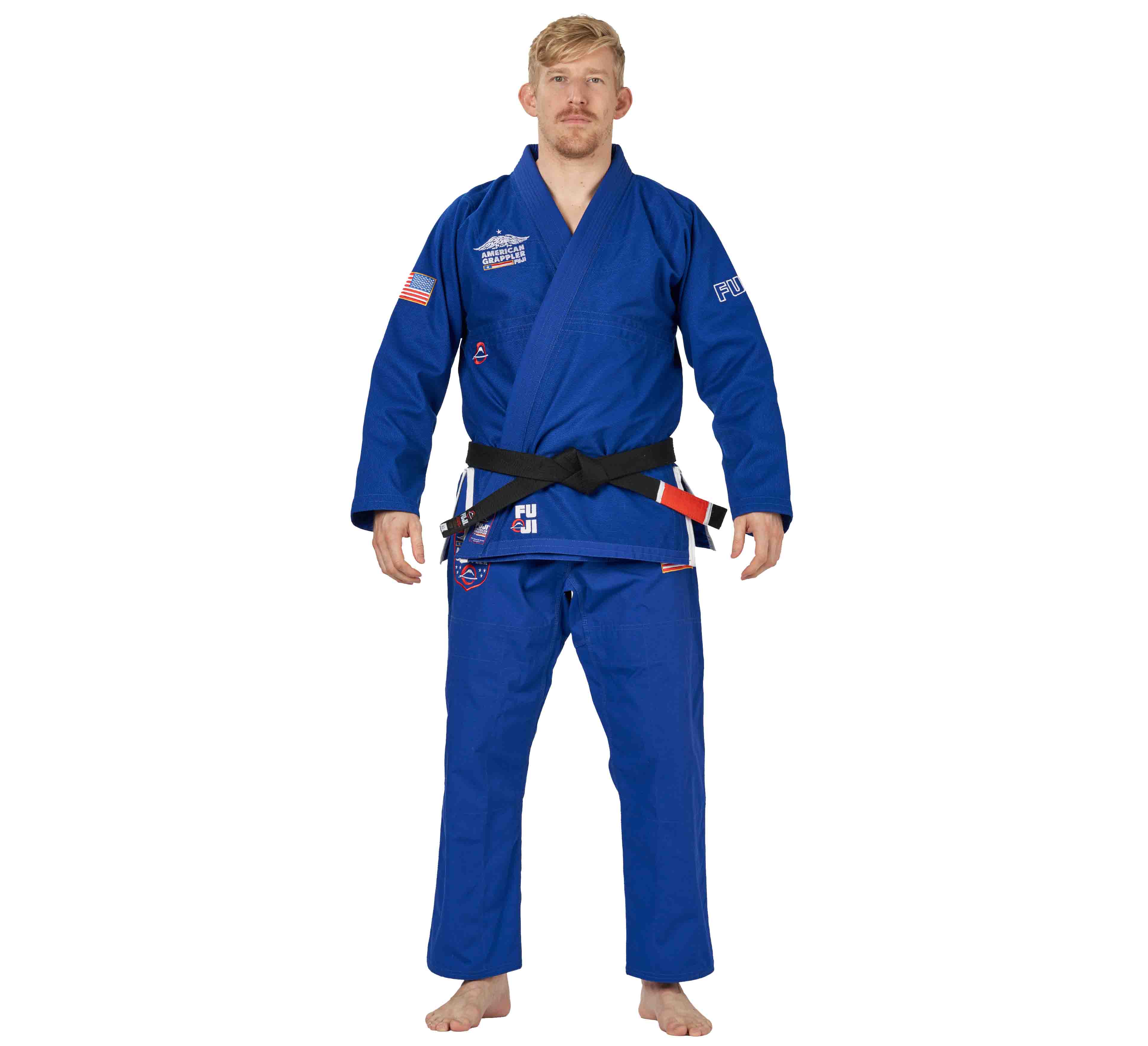 A man stands barefoot facing forward against a white background, wearing the Suparaito BJJ Gi American Grappler Blue with patches and a black belt.