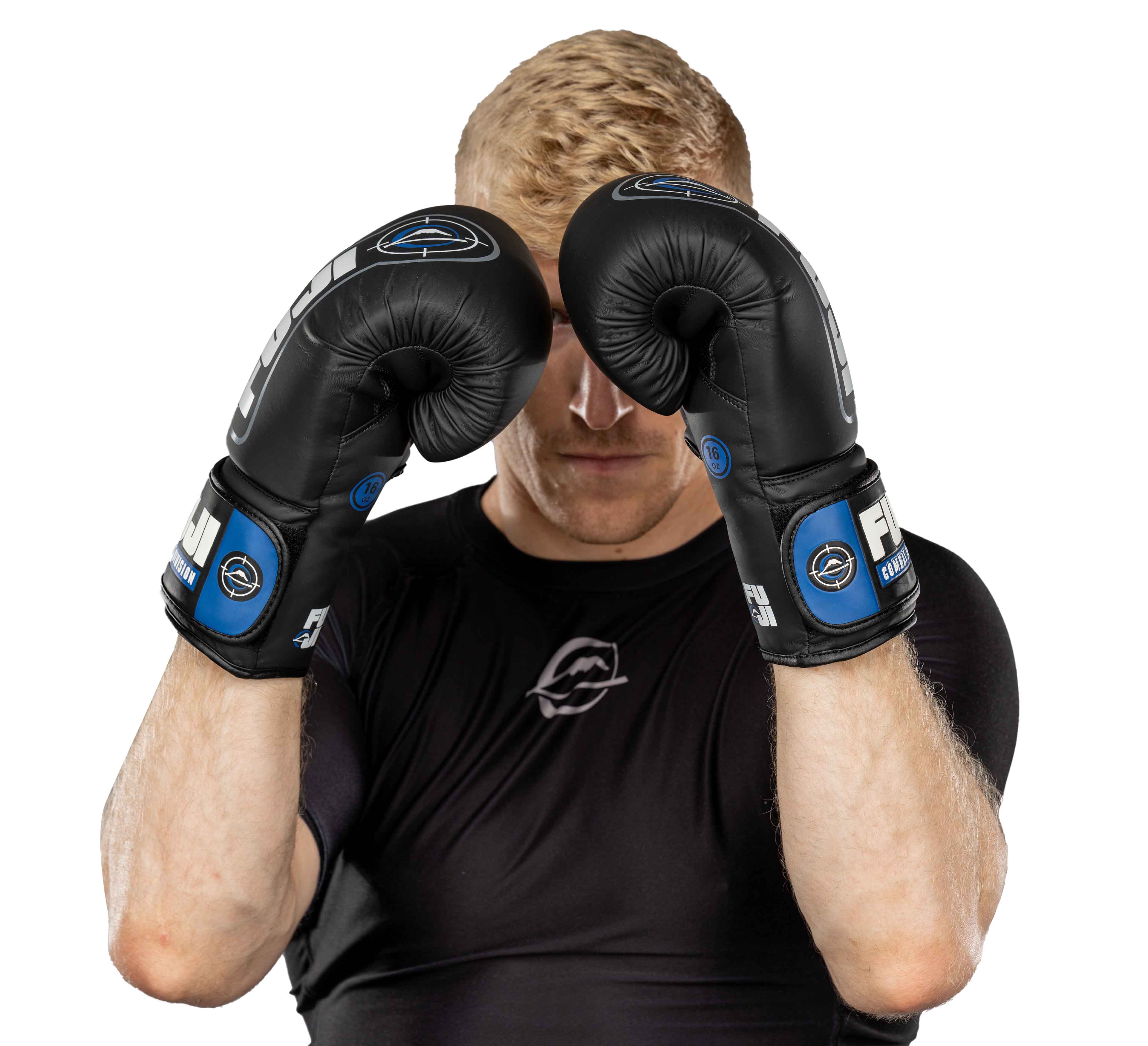 A person with short blond hair wears Precision Boxing Gloves Blue and a black athletic shirt, holding their fists up in a defensive boxing stance against a white background.