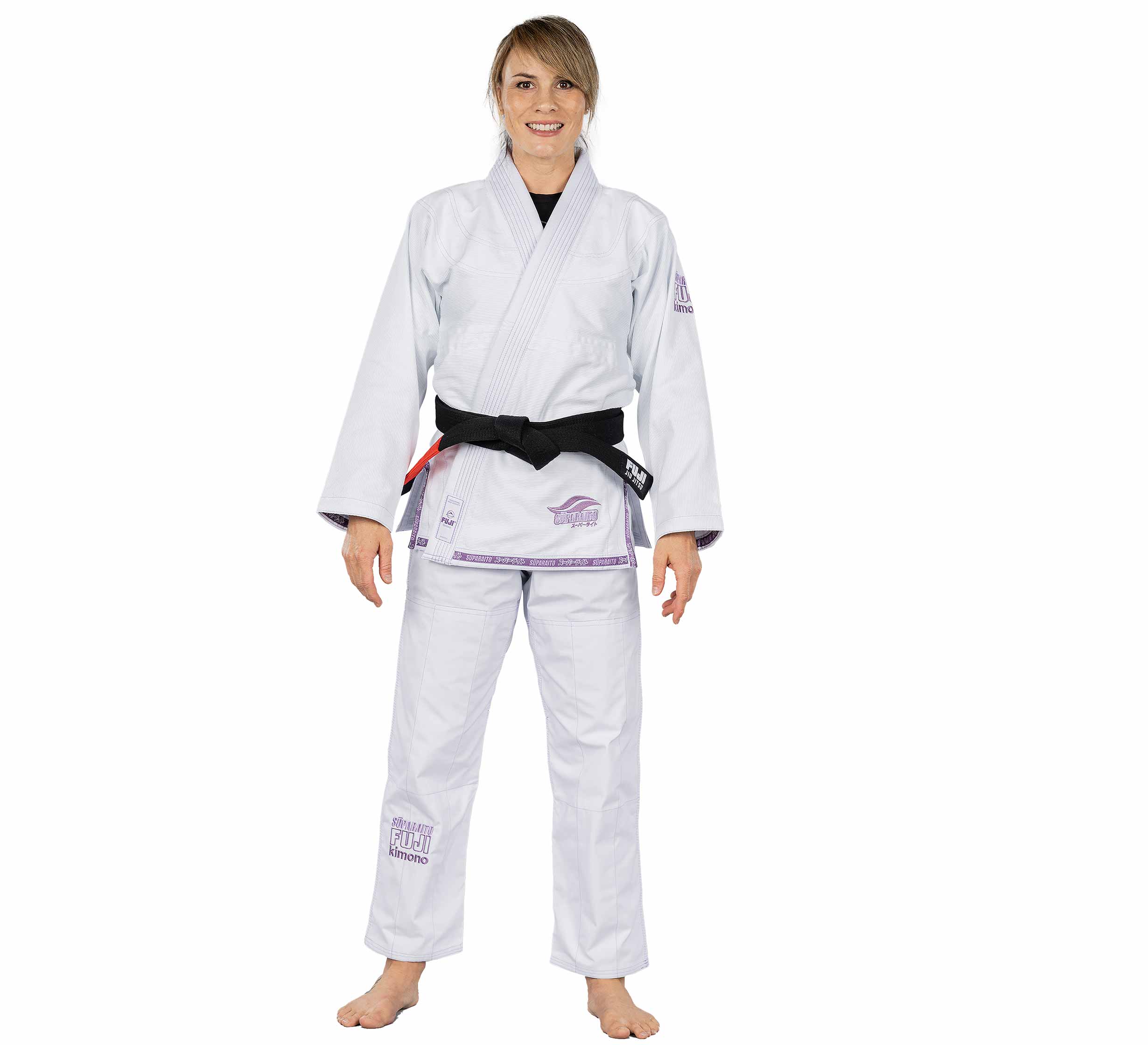 A woman stands barefoot, smiling and facing forward in a Suparaito Womens BJJ Gi in purple with a black belt, set against a plain white background.
