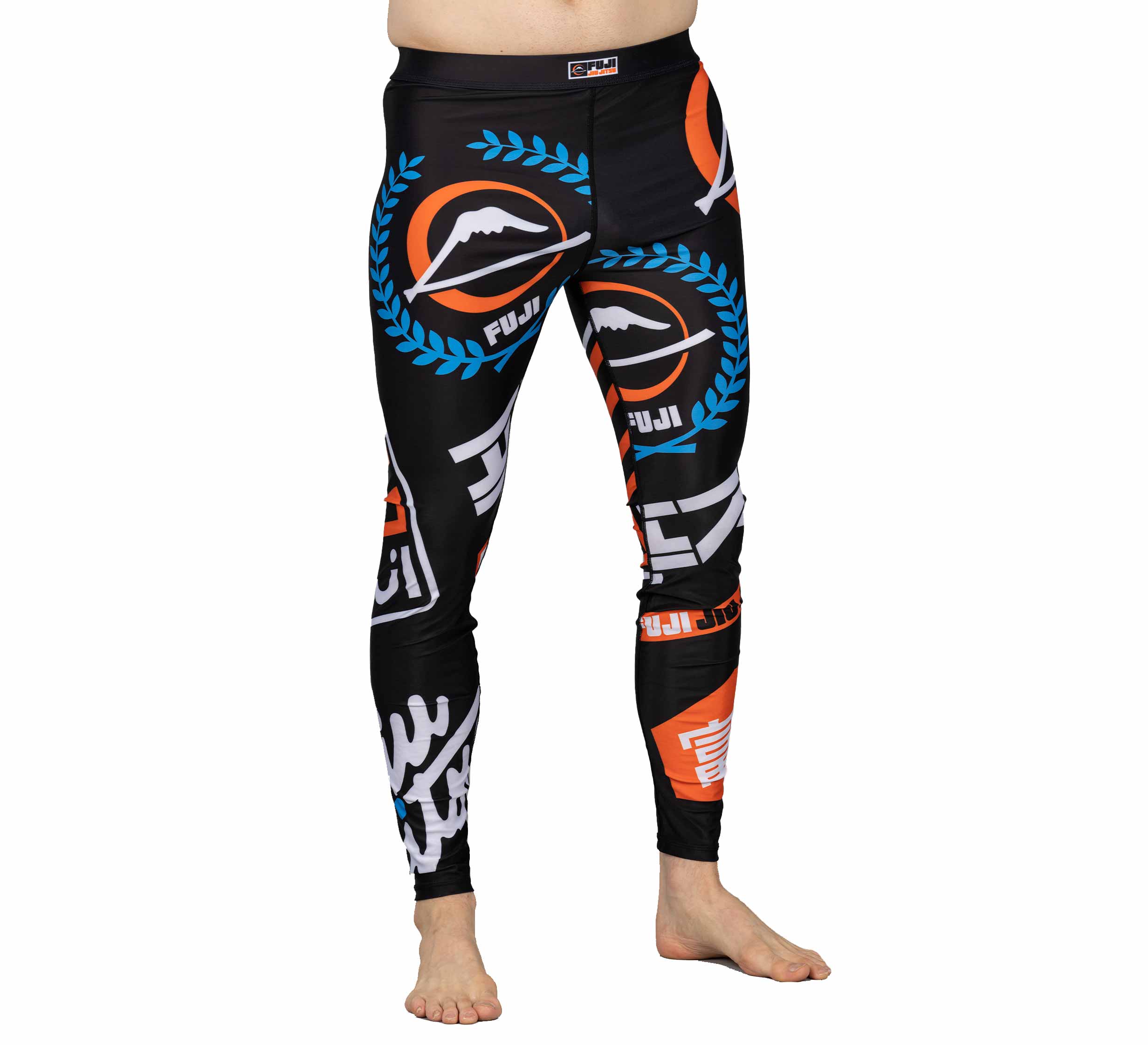 A person wearing XTR Extreme V1 Grappling Spats Black with bold orange, blue, and white Fuji logos and designs, standing barefoot against a white background.