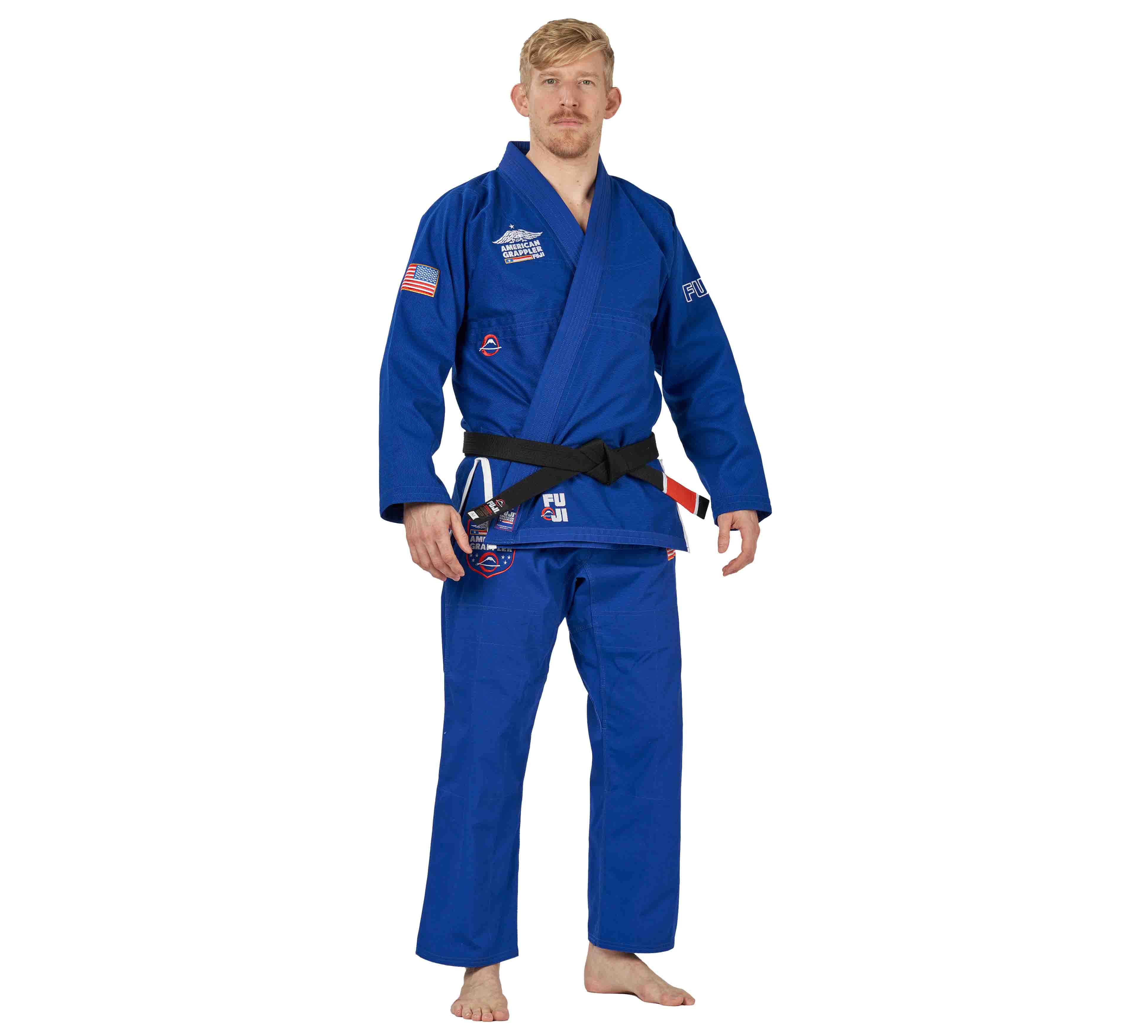 A man stands barefoot facing forward, wearing the Suparaito BJJ Gi American Grappler Blue with patches and a black belt, against a white background.