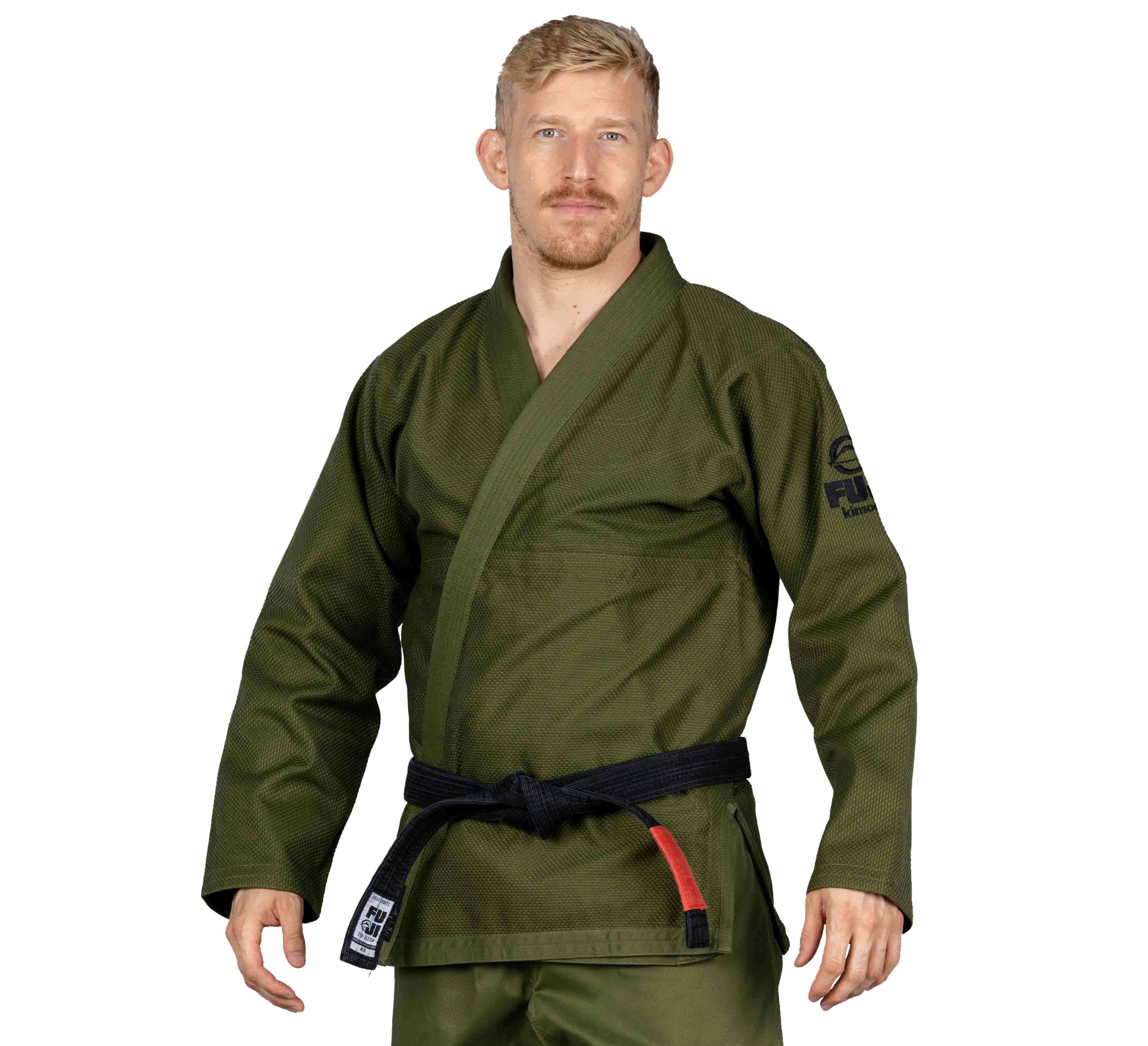 A man with short blond hair and a mustache stands facing the camera, wearing the All Around BJJ Gi Military Green with a black belt, against a plain white background.