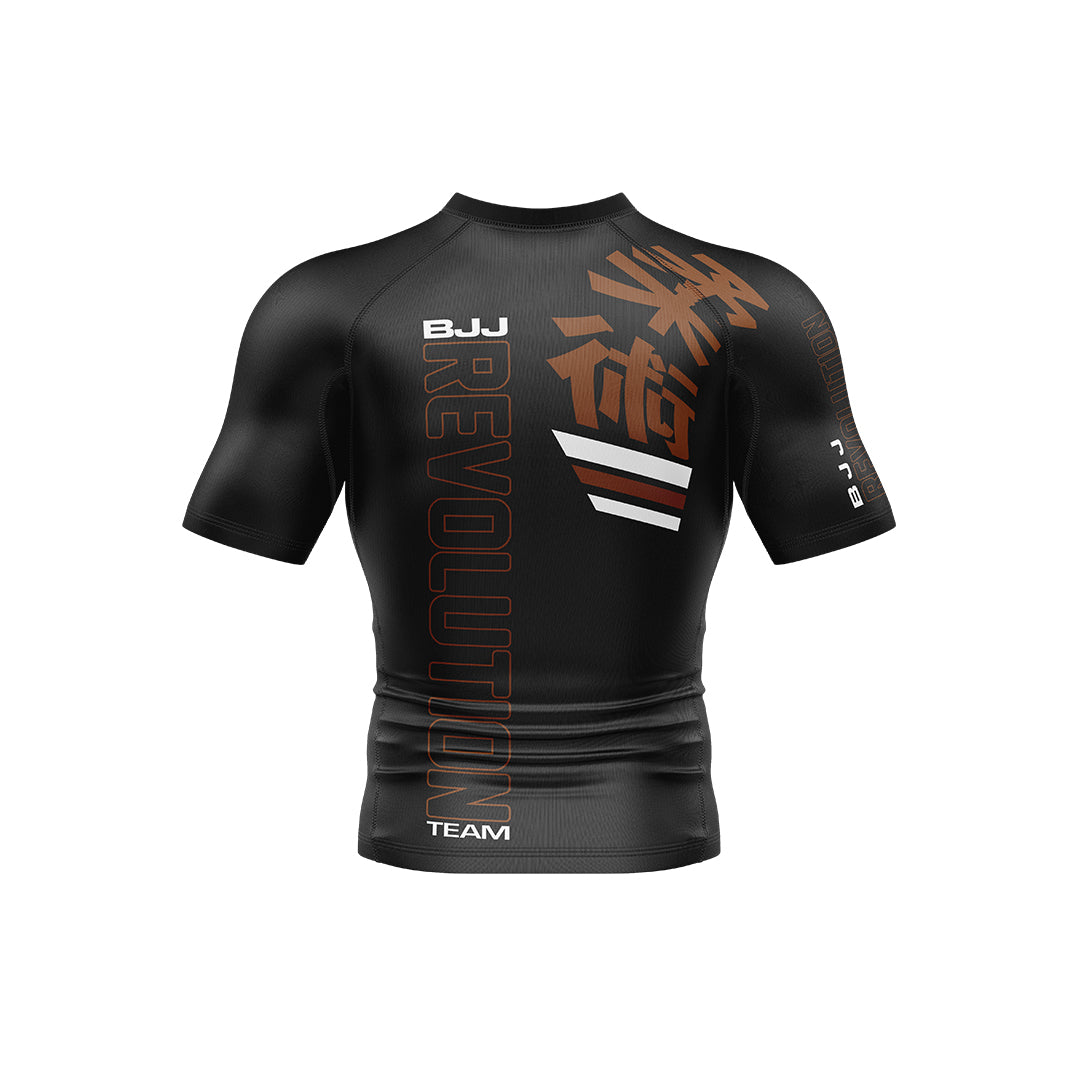 The BJJ Revolution Adult Ranked Short Sleeve Rashguard is black with bold orange “BJJ REVOLUTION” lettering, white stripes, and Japanese kanji on the right shoulder, shown against a white background.