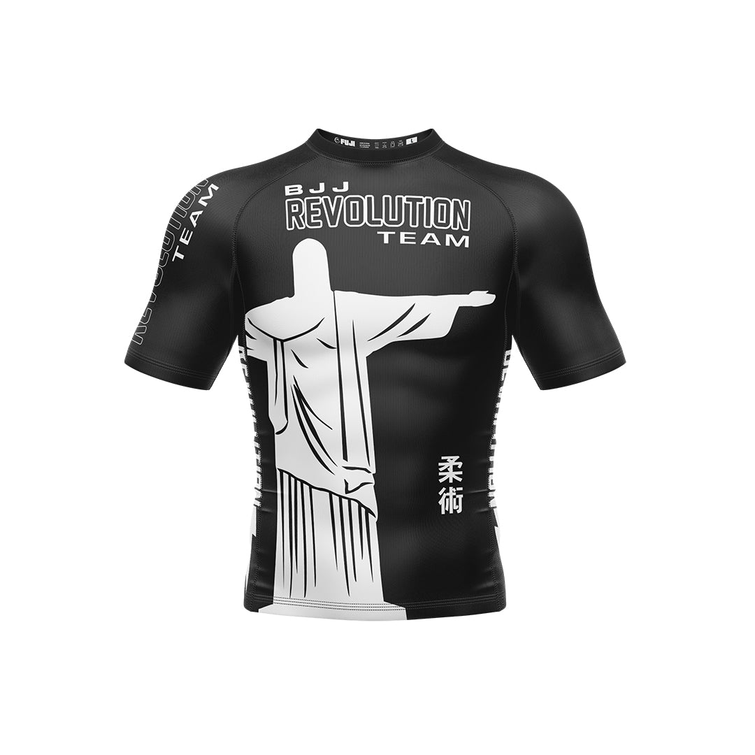 The BJJ Revolution Adult Ranked Short Sleeve Rashguard in black features a large white outline of Christ the Redeemer on the front, "BJJ Revolution Team" text above, and extra decorative text on the sleeves and sides.