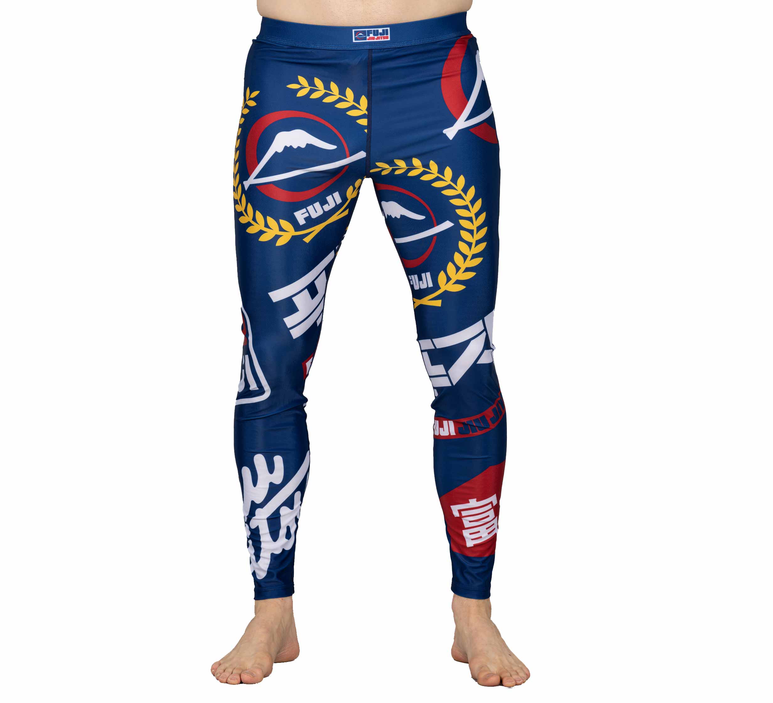 A person is wearing XTR Extreme V1 Grappling Spats Navy—full-length, blue athletic compression pants featuring bold mountain graphics, laurel wreaths, and Japanese-inspired white and red symbols. The wearer is barefoot.