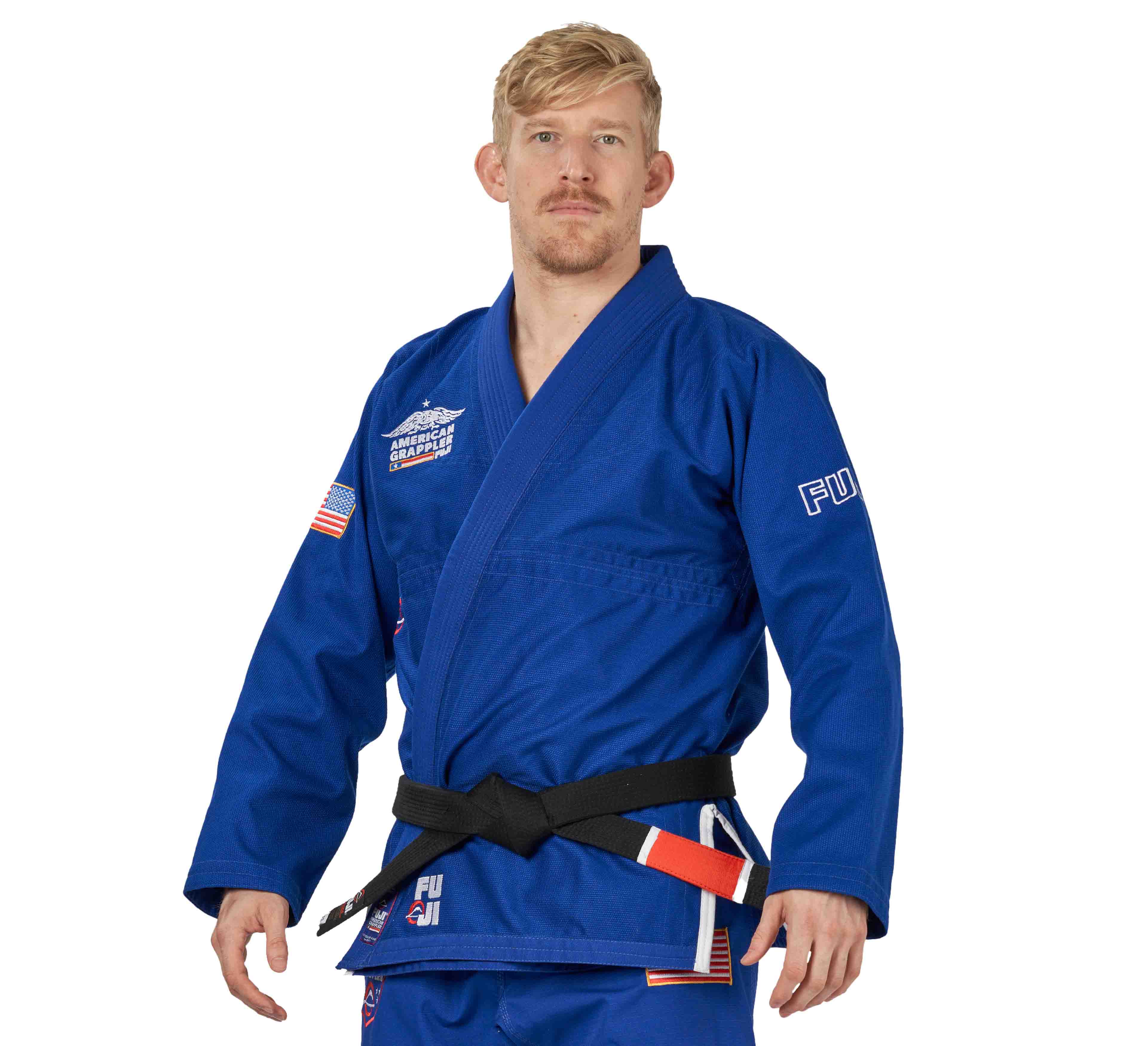 A person in the Suparaito BJJ Gi American Grappler Blue with patches and a black belt stands facing forward against a white background.