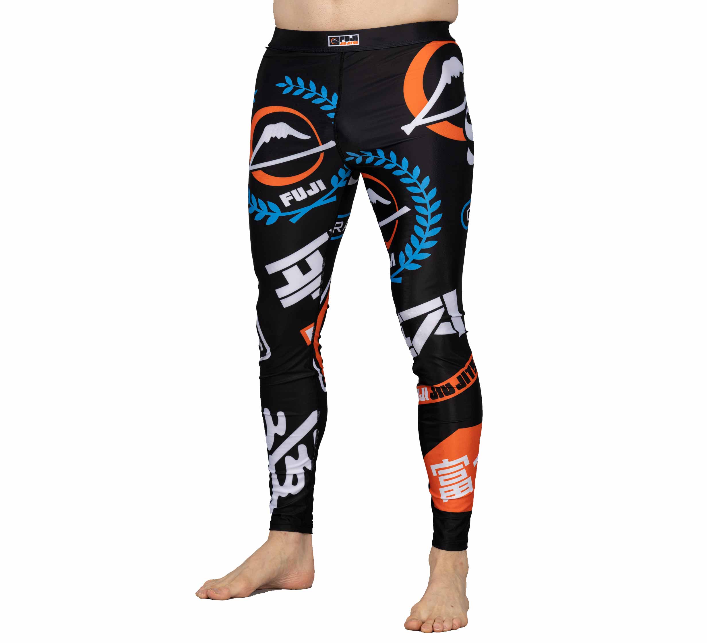 A person is wearing XTR Extreme V1 Grappling Spats Black, featuring colorful blue, orange, and white logos and text designs, standing barefoot against a white background.