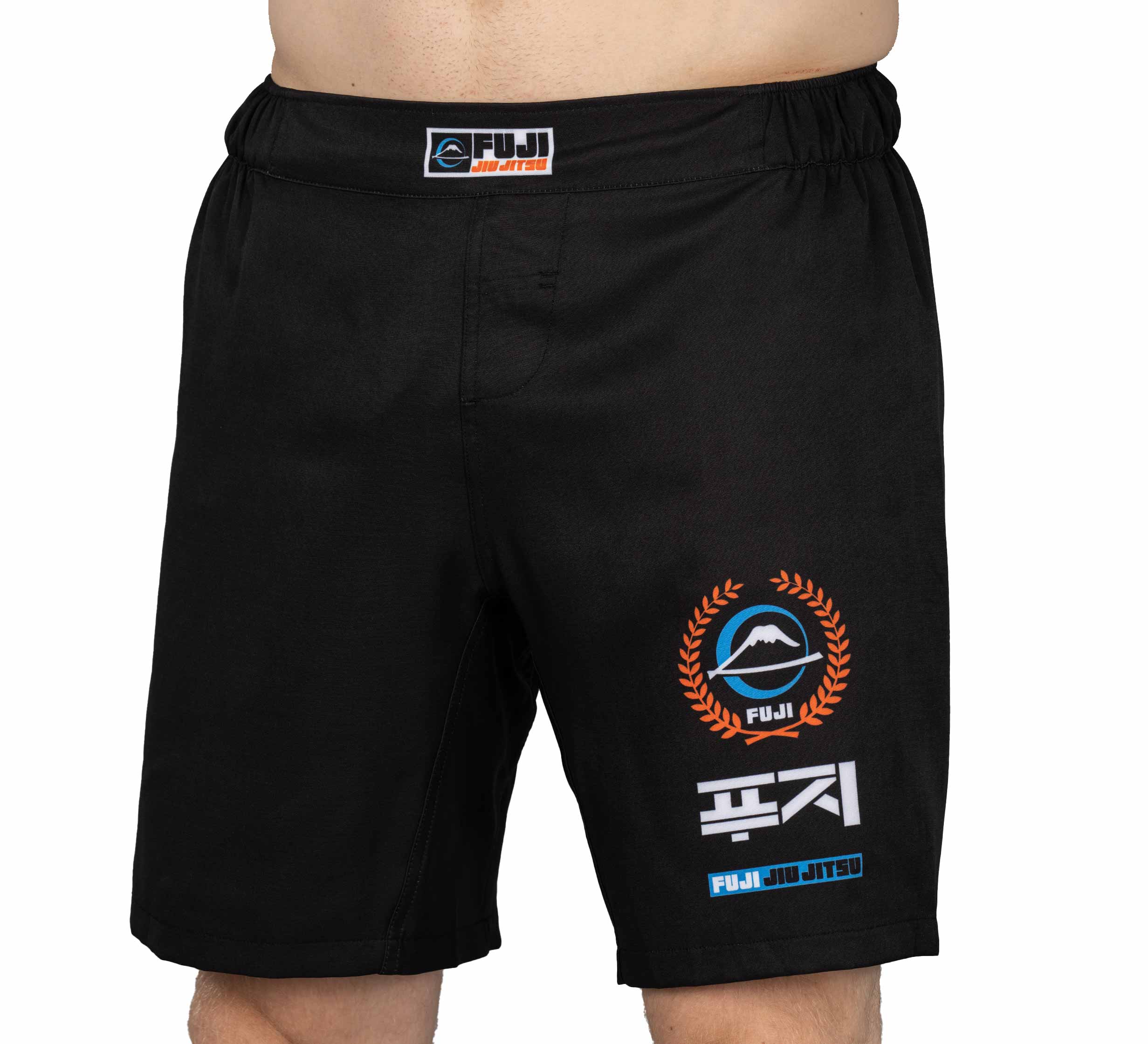 A person wearing black XTR Extreme Grappling Fight Shorts with a mountain, laurel wreath, and Korean characters printed on the right leg. The Fuji brand label is visible on the waistband.