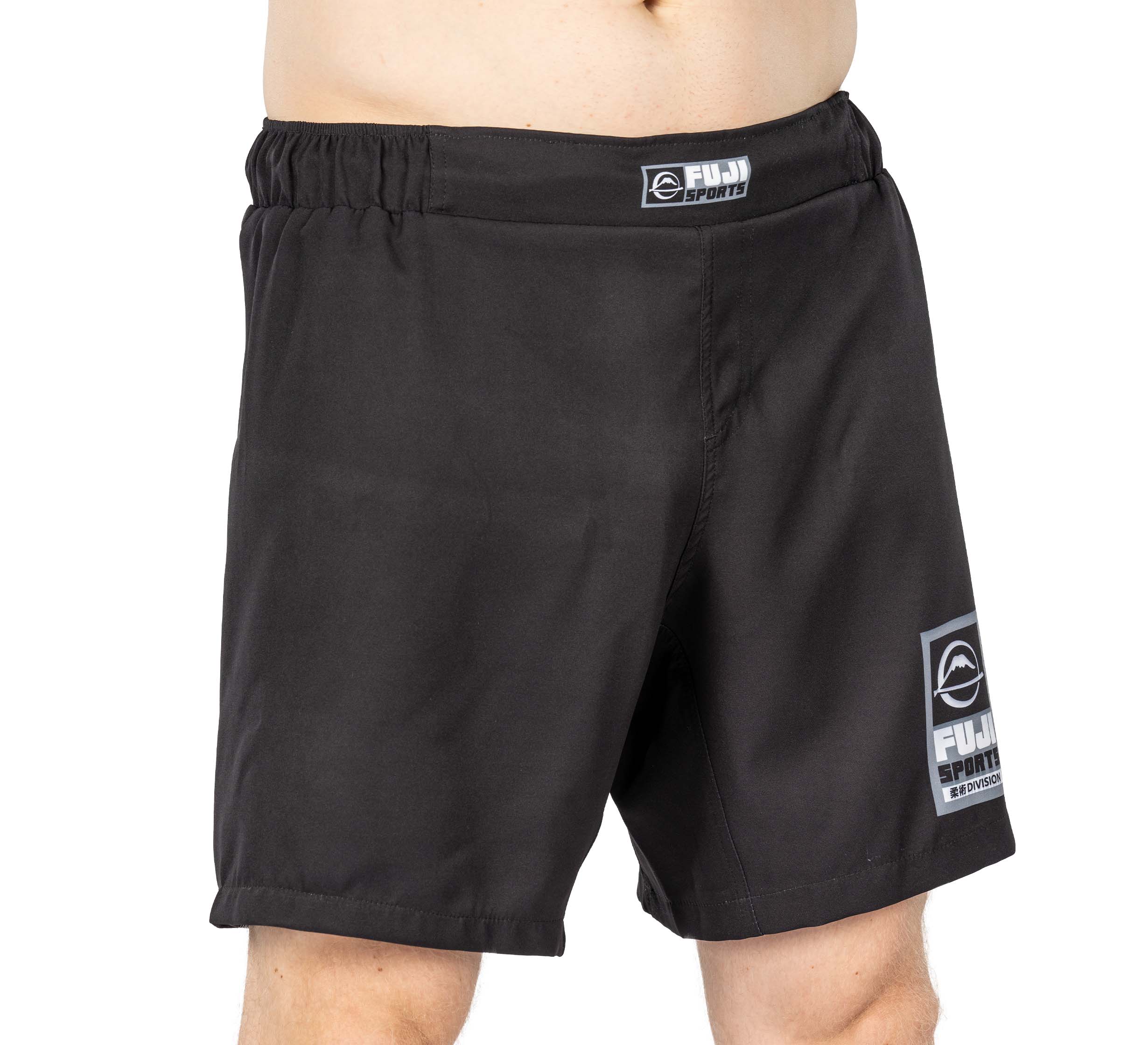 Someone wearing the Ultimate Grappling Shorts Black with an elastic waistband and two FUJI SPORT logos—one on the waistband, one on the lower left leg. Only part of their upper body is visible.