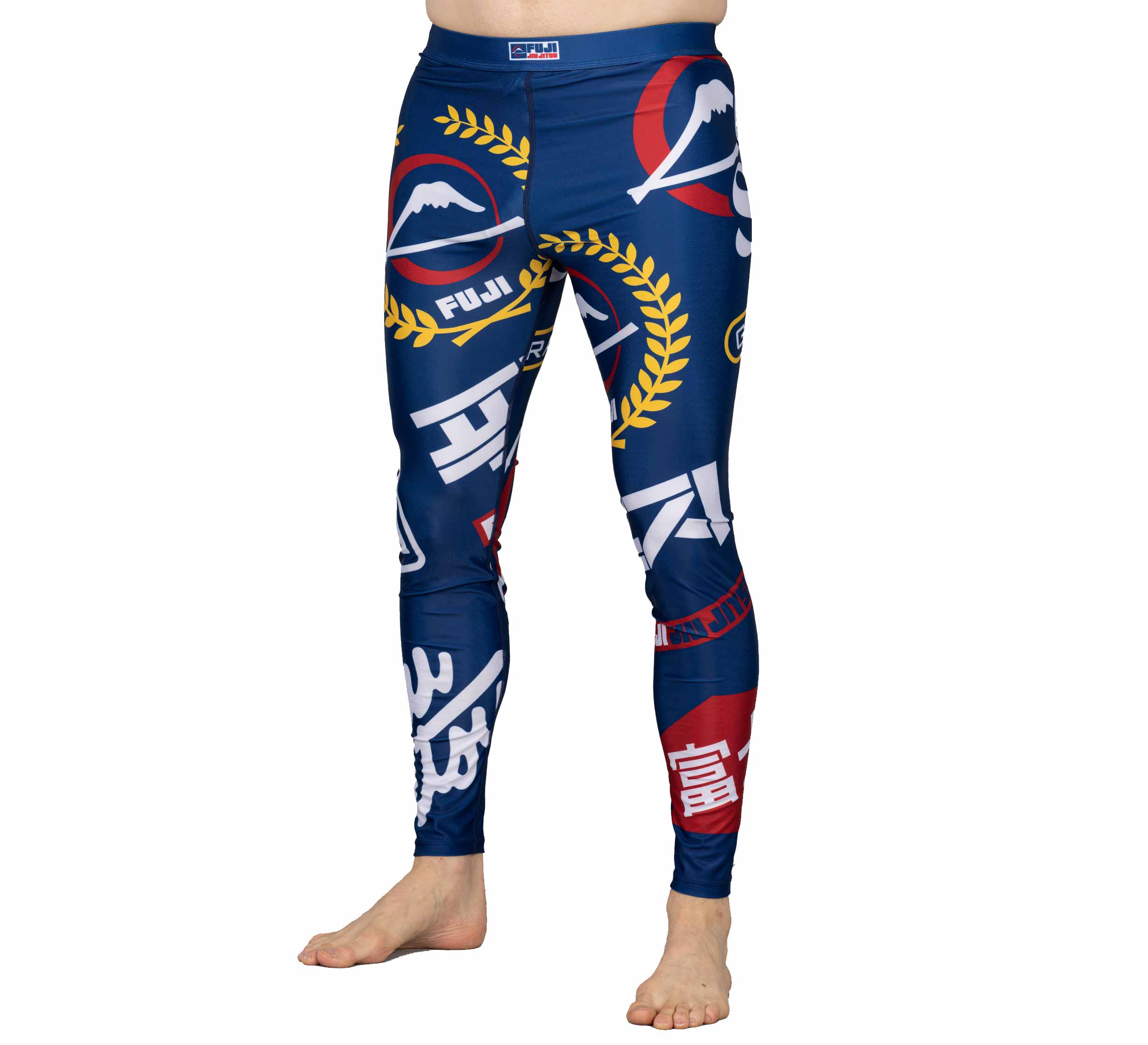A person wearing XTR Extreme V1 Grappling Spats Navy featuring various logos, white and red Japanese characters, yellow laurel wreaths, and a mountain graphic stands barefoot against a white background.