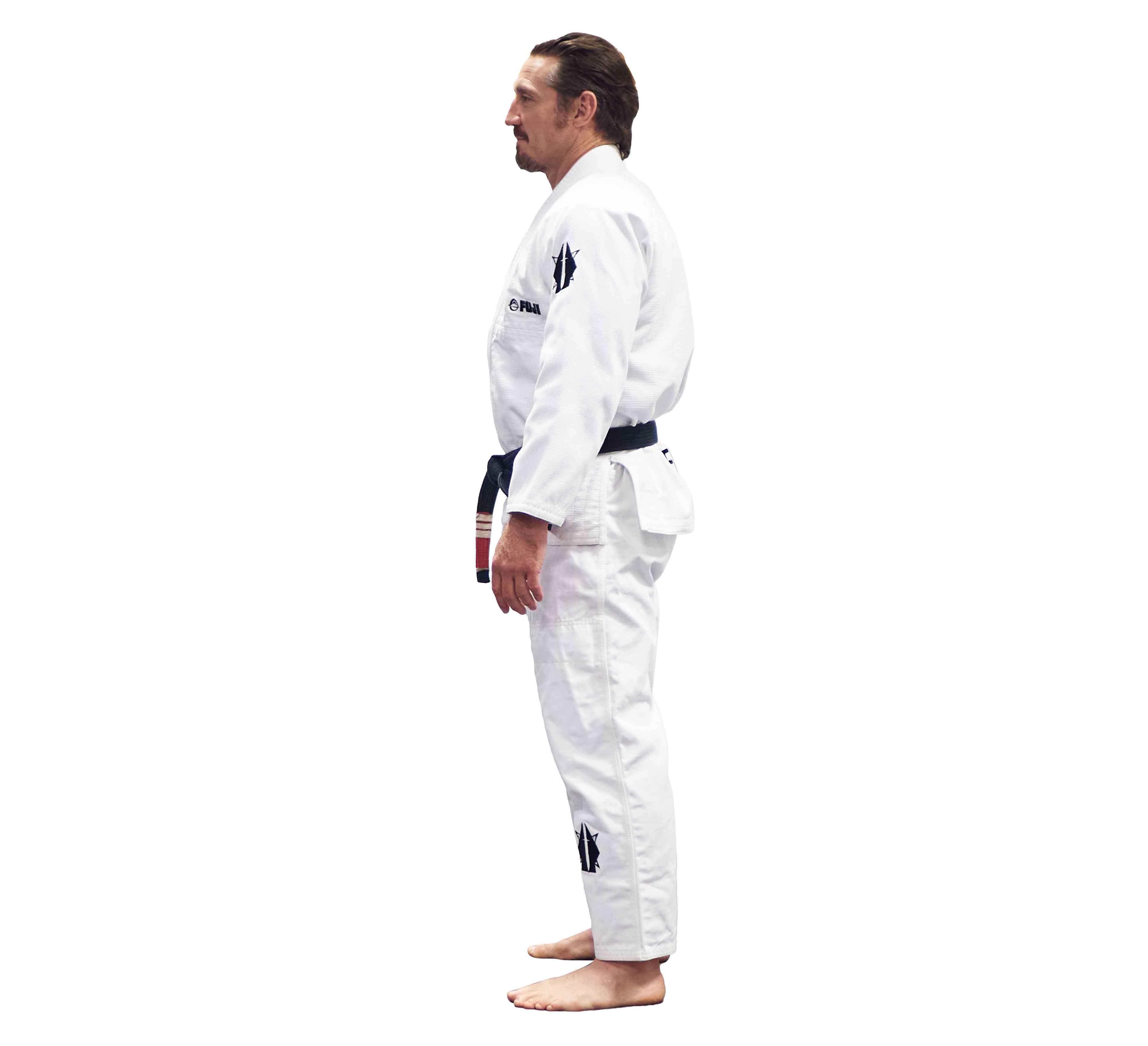 A man stands barefoot in a side profile pose wearing the Lightweight BJJ Gi Sheepdog Response Edition White with a black belt against a plain white background.