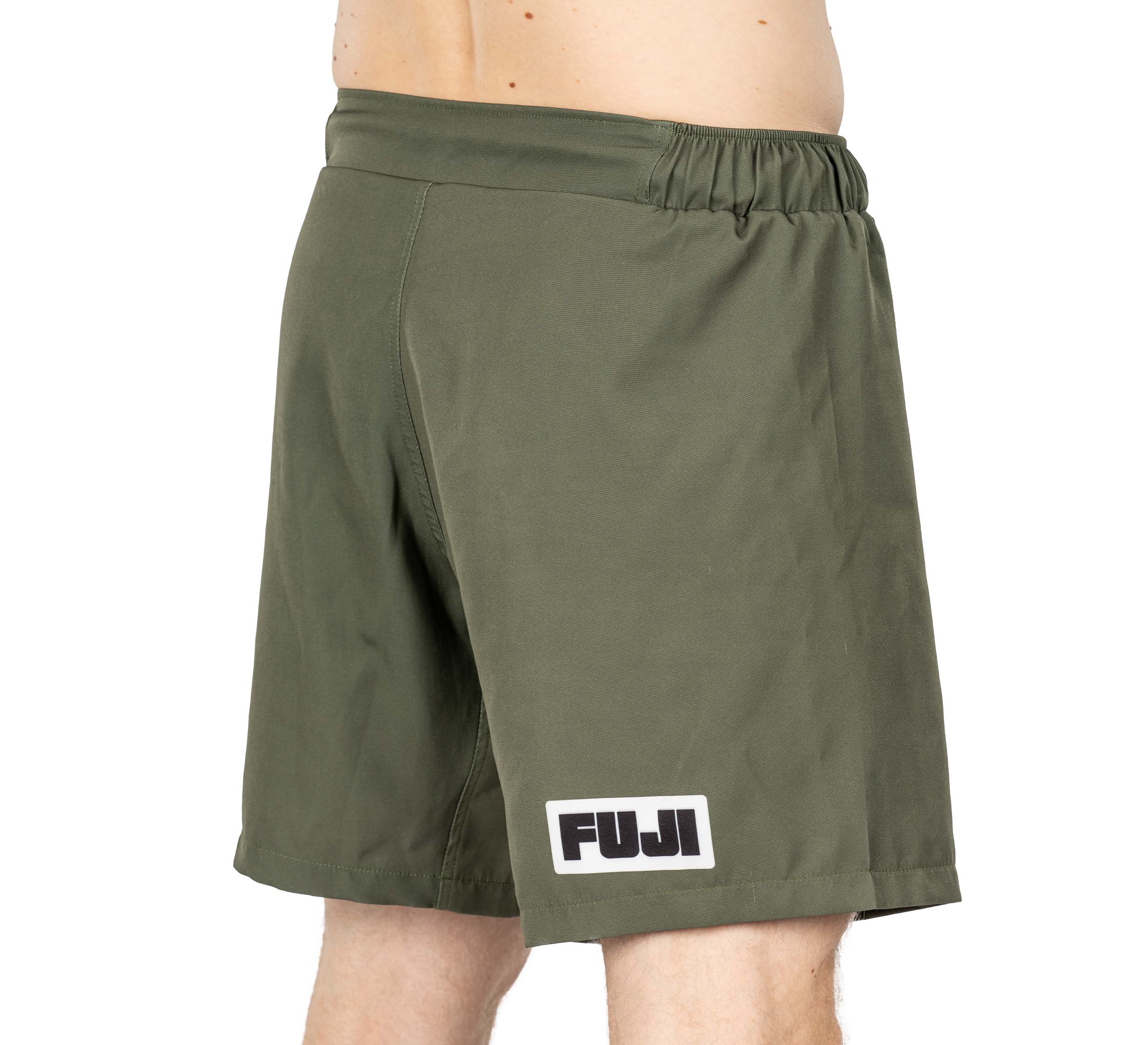 Someone wearing Ultimate Grappling Shorts Military Green, featuring an elastic waistband and a FUJI logo patch near the left hem.