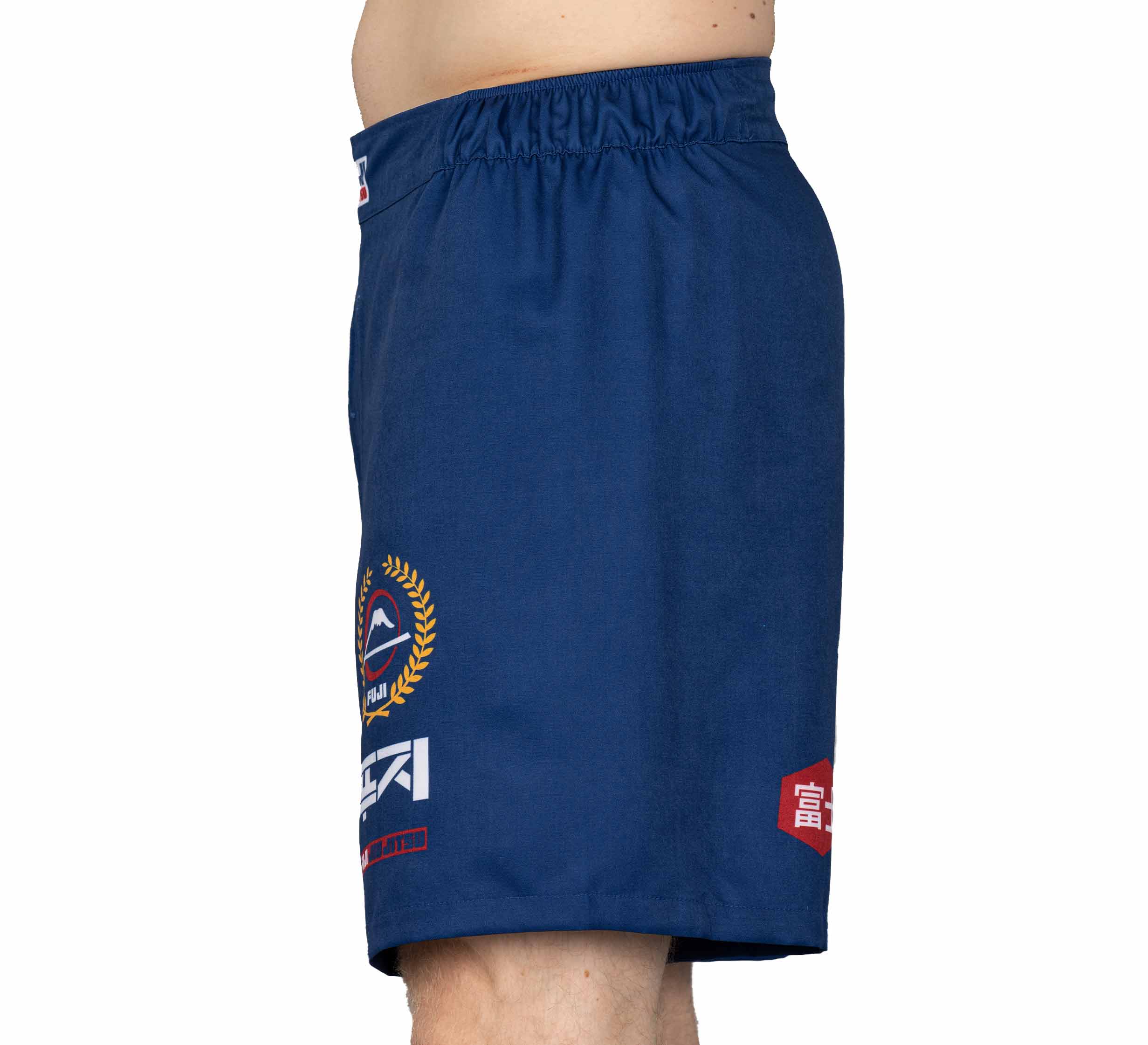 A person wearing XTR Extreme Grappling Fight Shorts Navy, featuring multiple logos and designs on the left side, is photographed from the side against a plain white background.