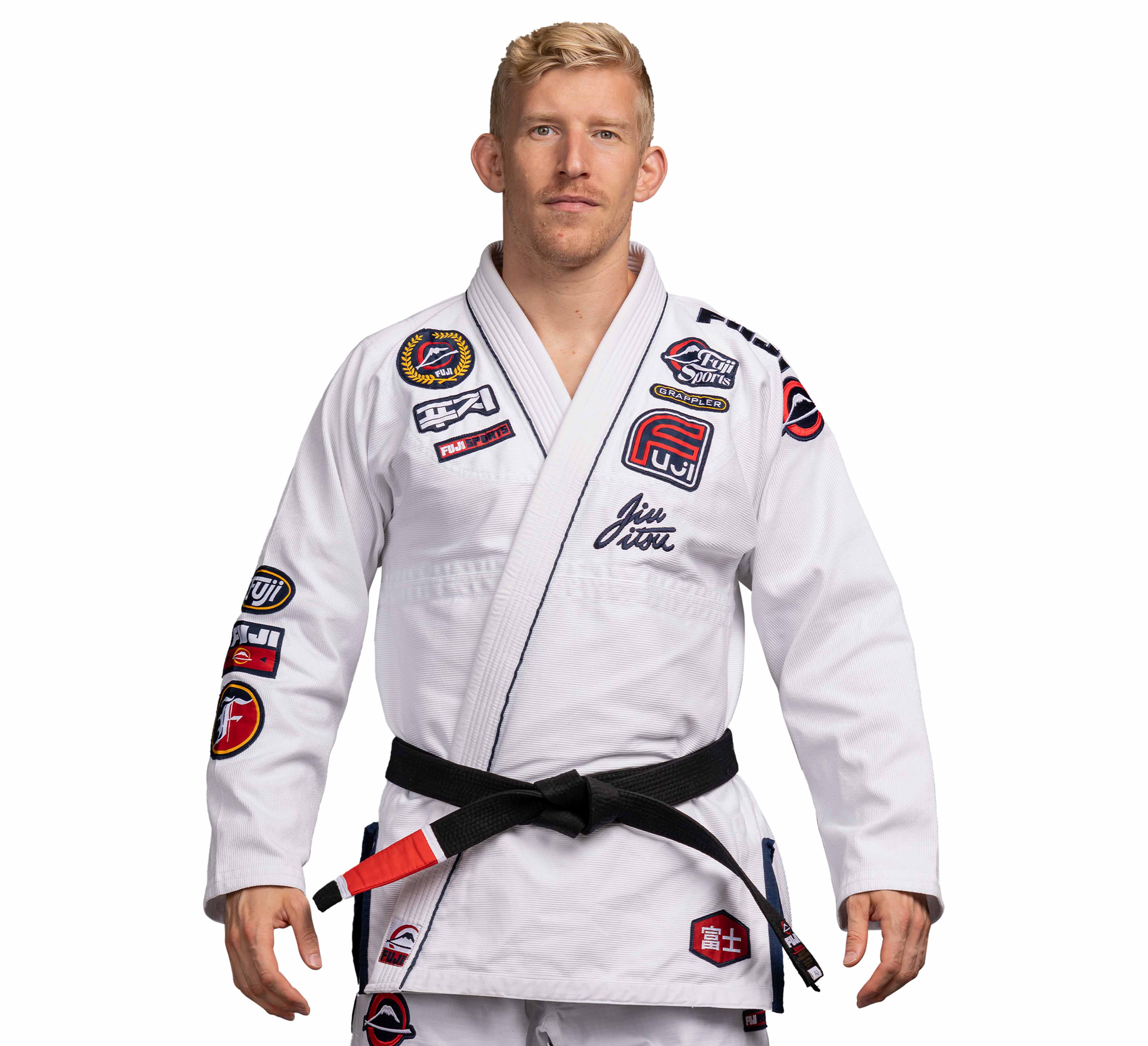 A man stands facing forward against a white background, wearing the Suparaito BJJ Gi XTR Edition White with various patches and a black belt.