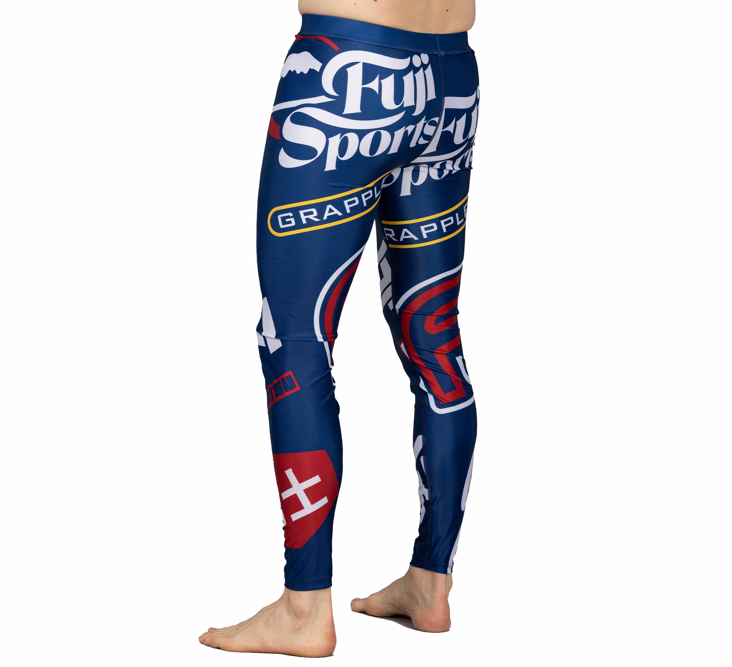 A person stands barefoot in XTR Extreme V1 Grappling Spats Navy, featuring bold white and red graphic text and logos, including Fuji Sports and Grapple, against a plain white background.