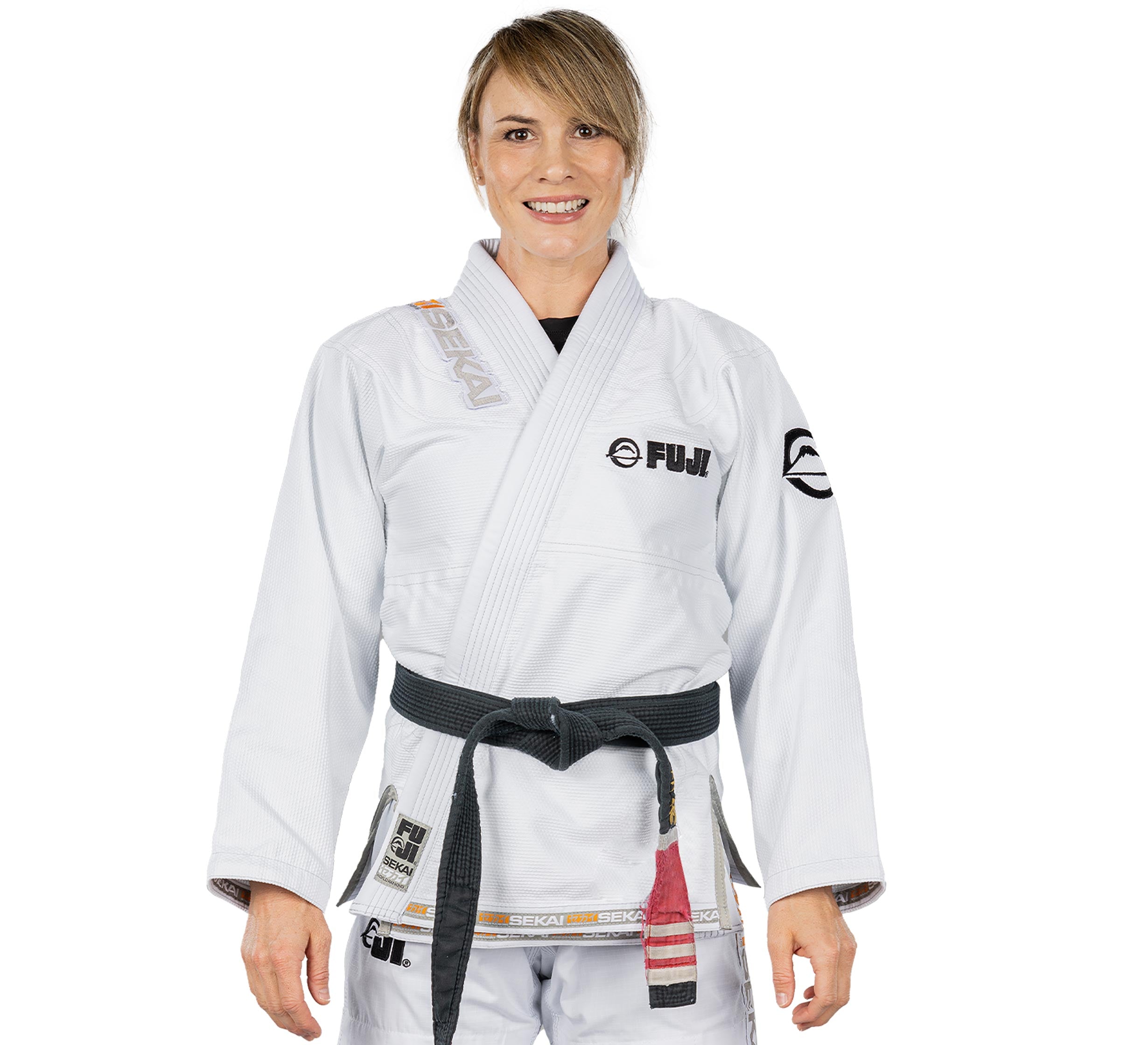 A woman wearing the Sekai 2.0 Womens BJJ Gi White with sponsor logos and a black belt stands smiling against a plain white background.