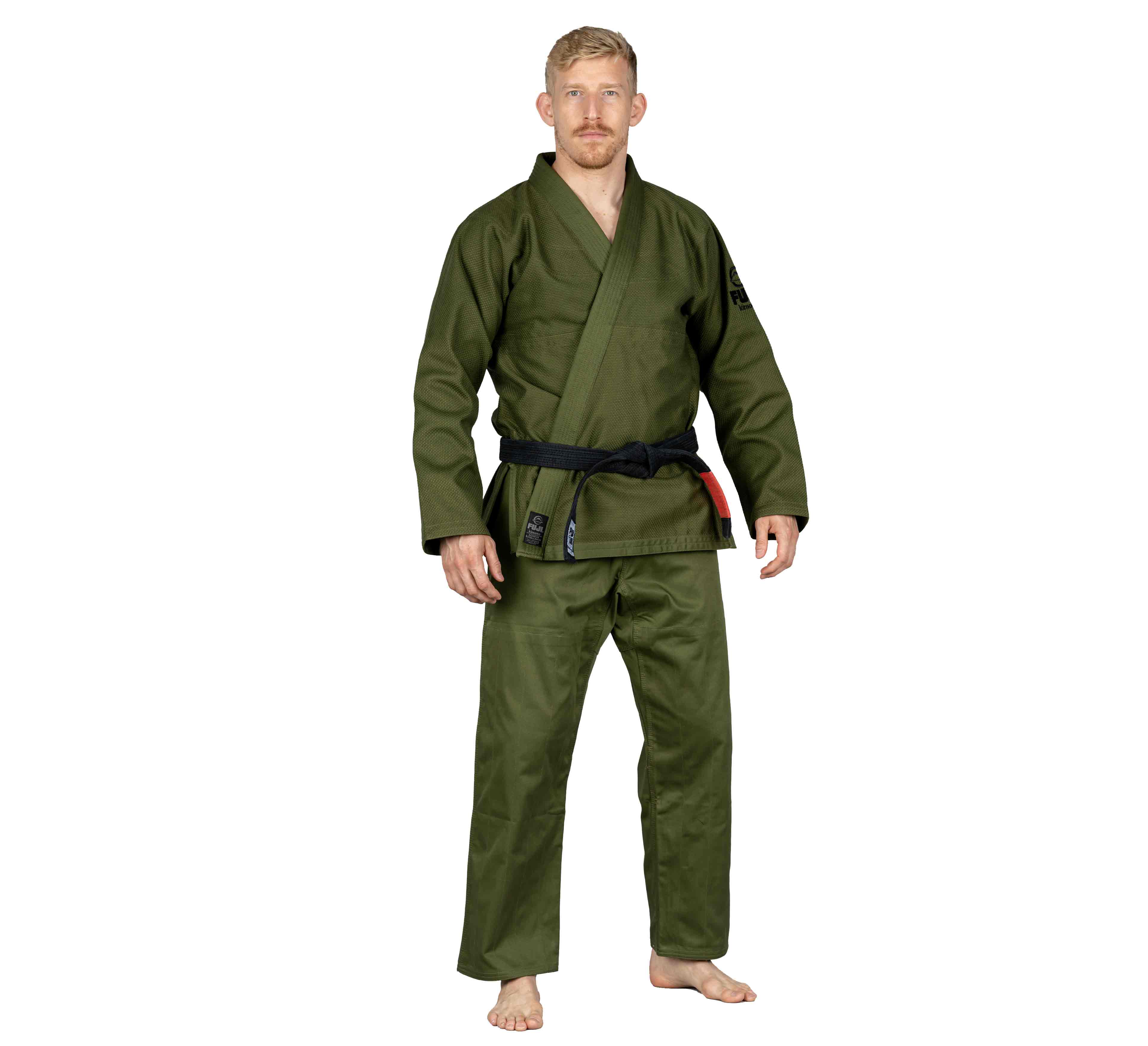 A man stands barefoot in the All Around BJJ Gi Military Green with a black belt featuring red detail. He faces forward with a neutral expression against a plain white background.
