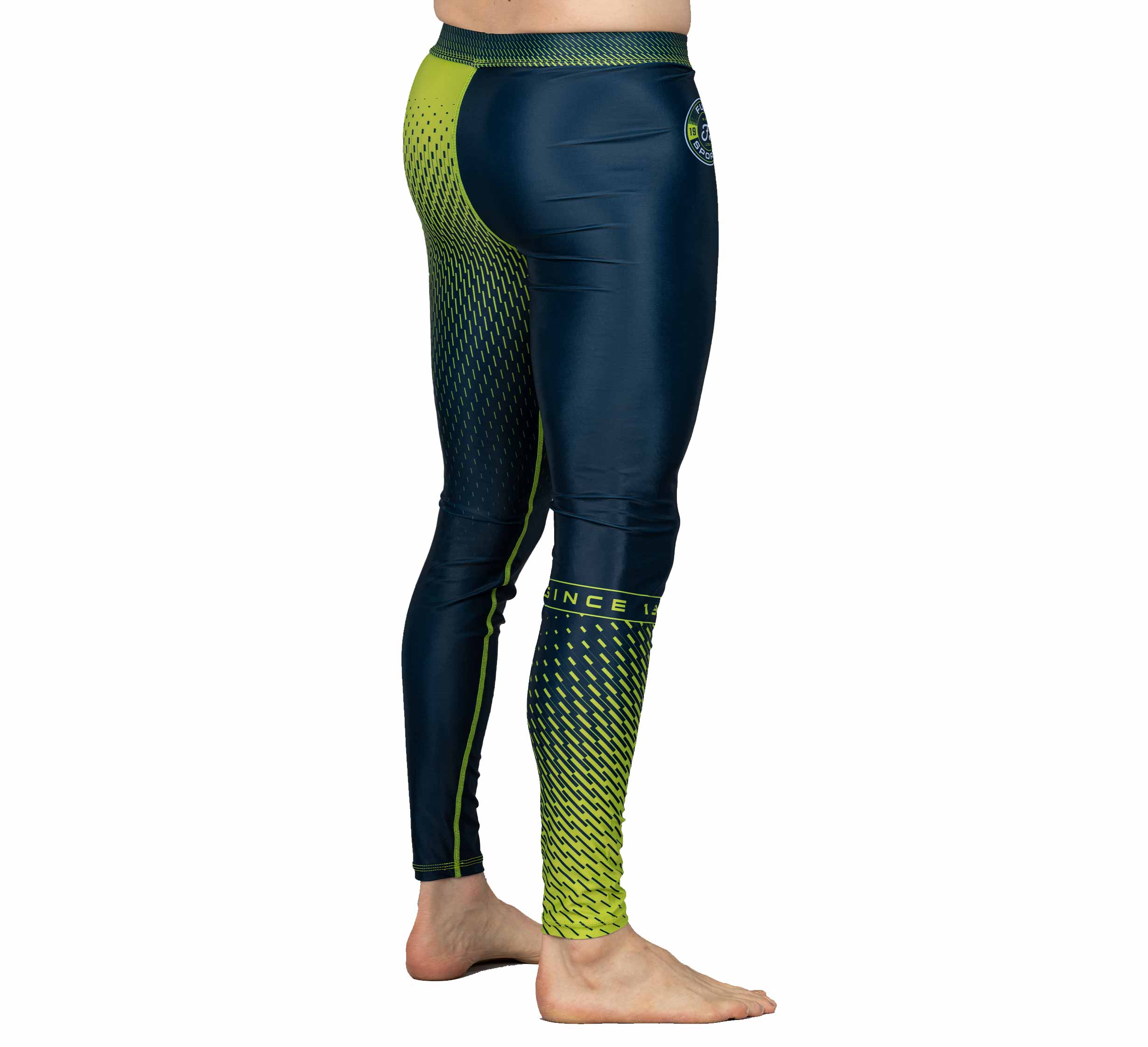 A person stands barefoot in Match Grappling Spats Navy, featuring a geometric pattern and logo on the waist, shown from the side against a white background.