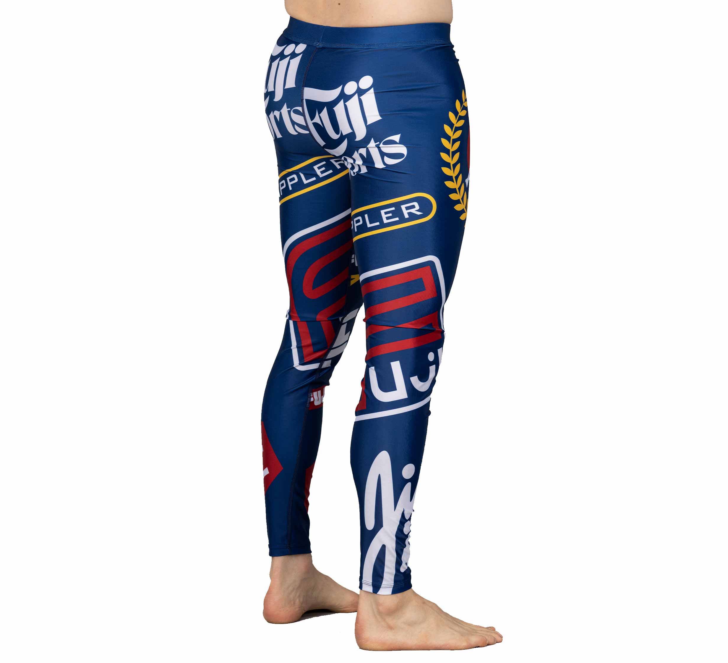Shown from the side, only lower torso and legs visible, a barefoot person wears the XTR Extreme V1 Grappling Spats Navy—fitted leggings featuring bold white, red, and yellow graphic prints with prominent brand logos.