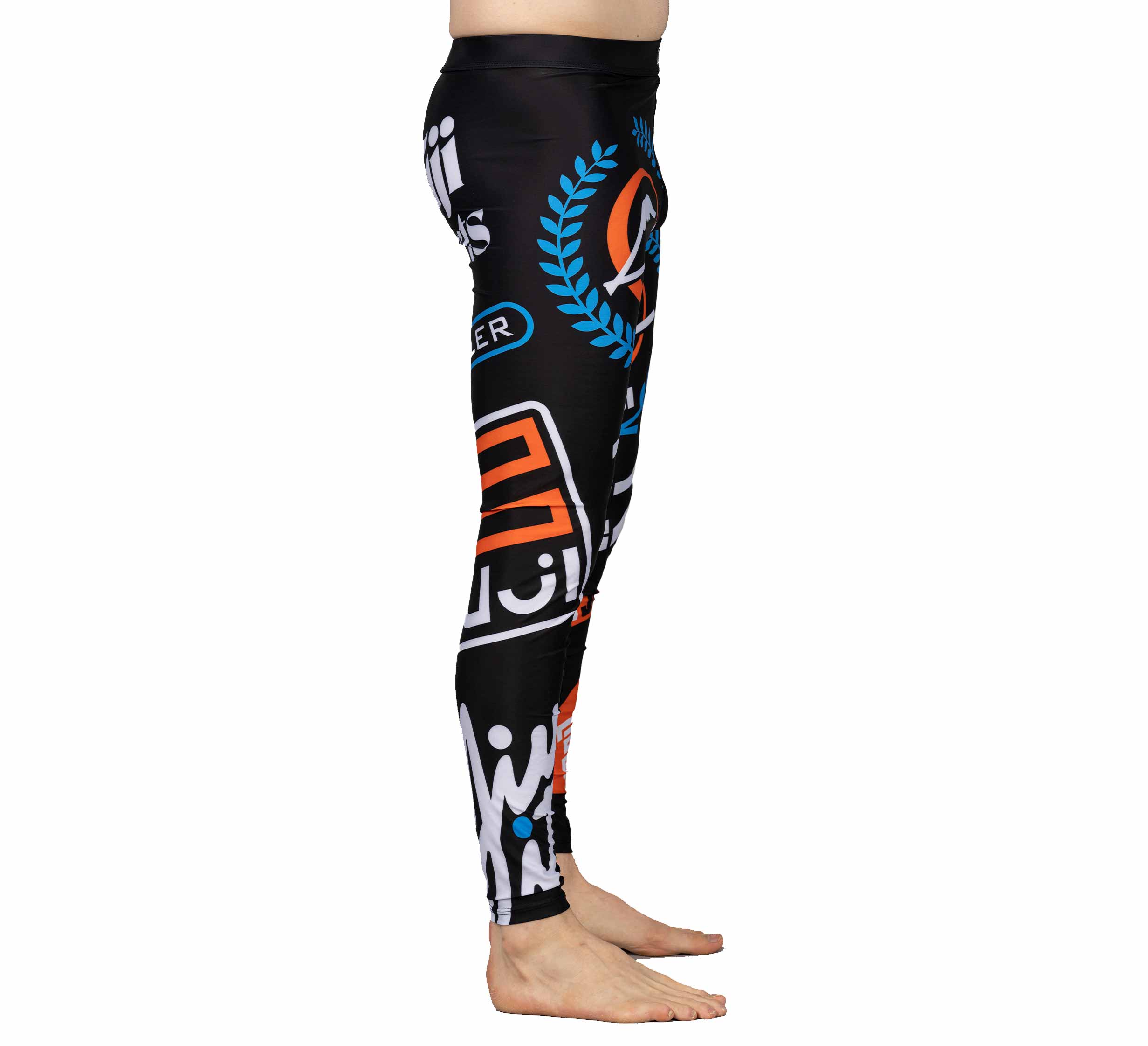 A person stands barefoot in XTR Extreme V1 Grappling Spats Black, featuring colorful abstract graphics and text, shown from the side on a white background.