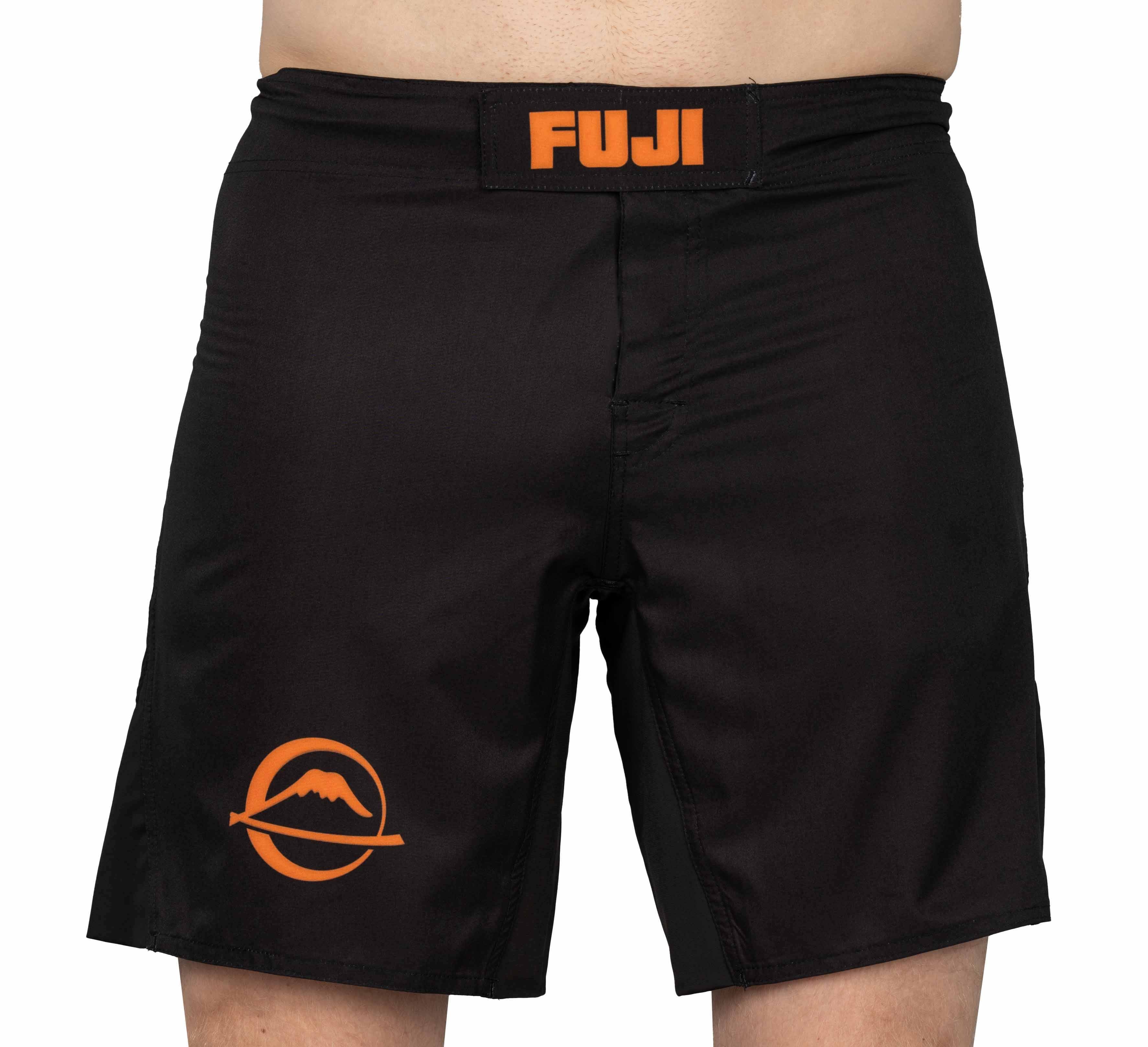 Baseline Fight Shorts Black/Orange featuring orange FUJI text on the waistband and an orange mountain logo on the left leg. Shown worn from waist to mid-thigh.