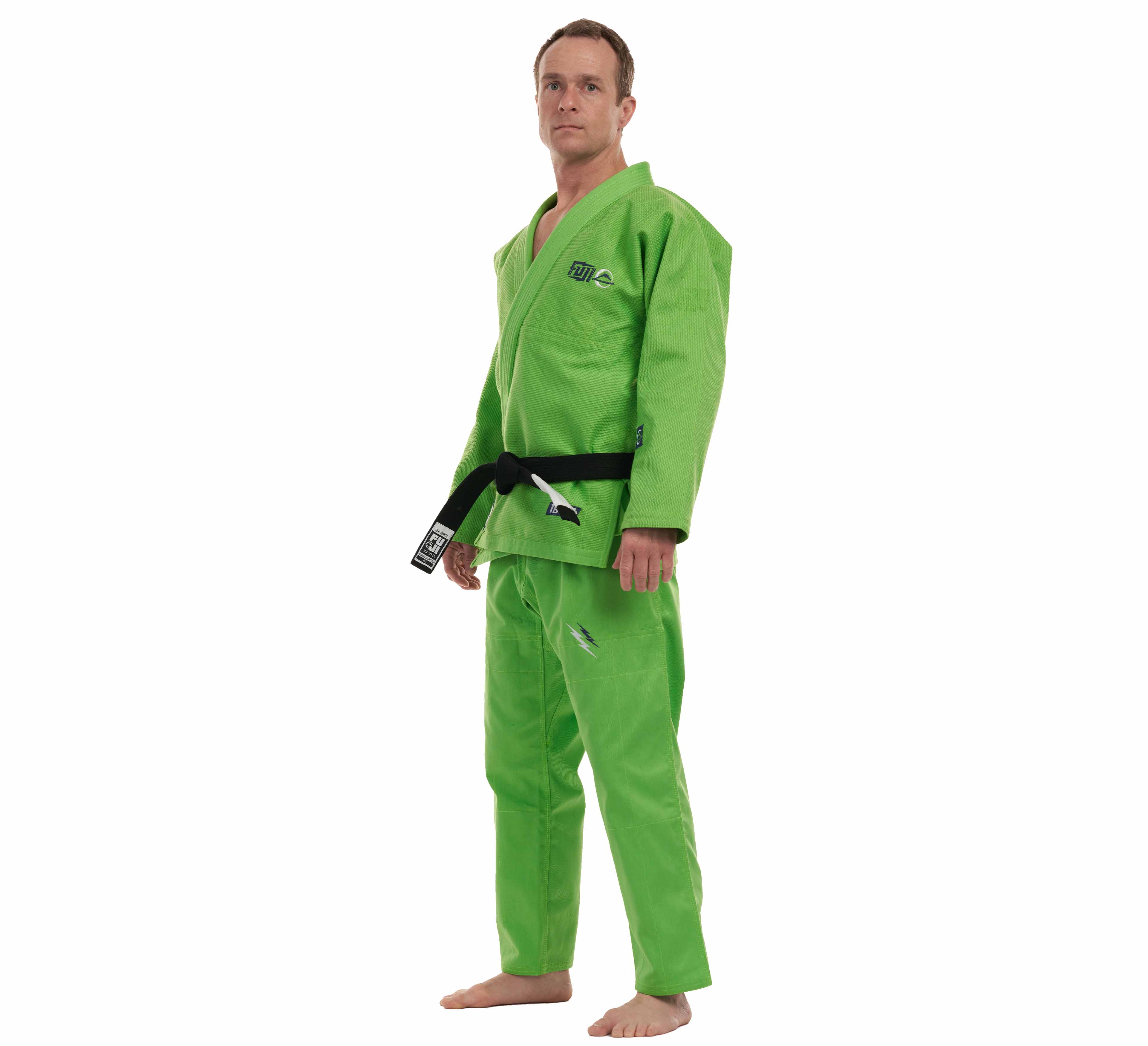 A person stands barefoot in the All Around BJJ Gi Electric Green Edition with a black belt, facing slightly to the side against a plain white background.