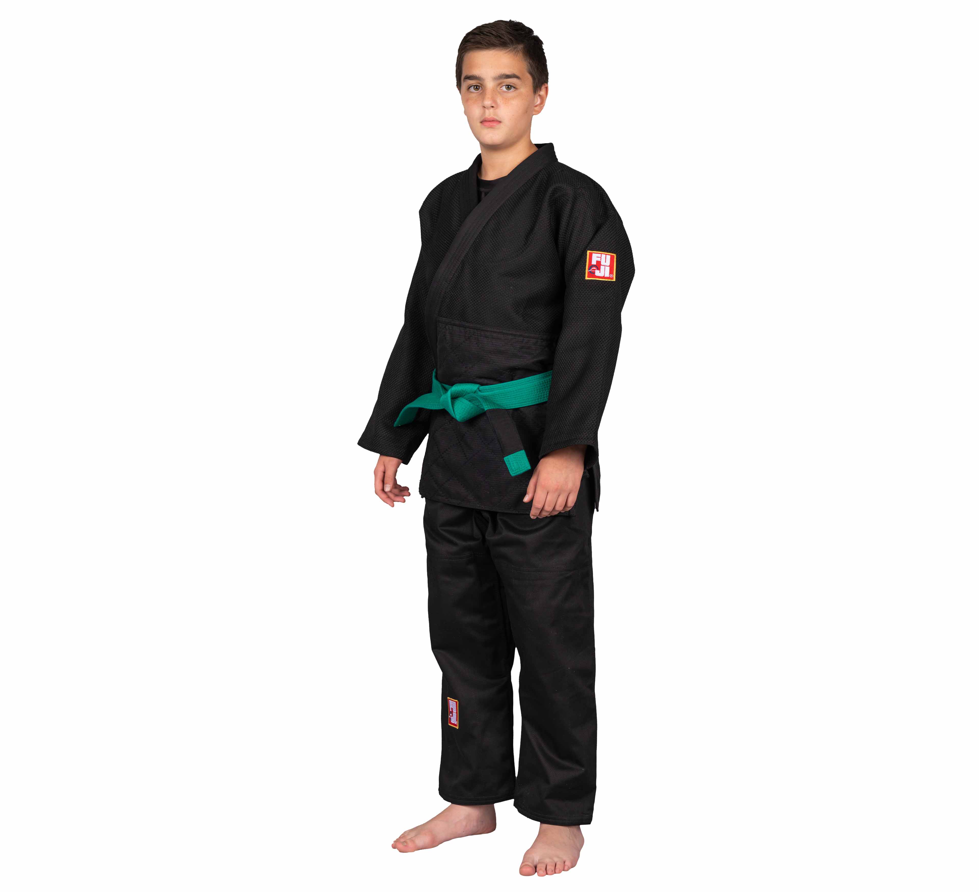 A young boy stands barefoot against a white background, wearing a Single Weave Judo Gi Black with a green belt.