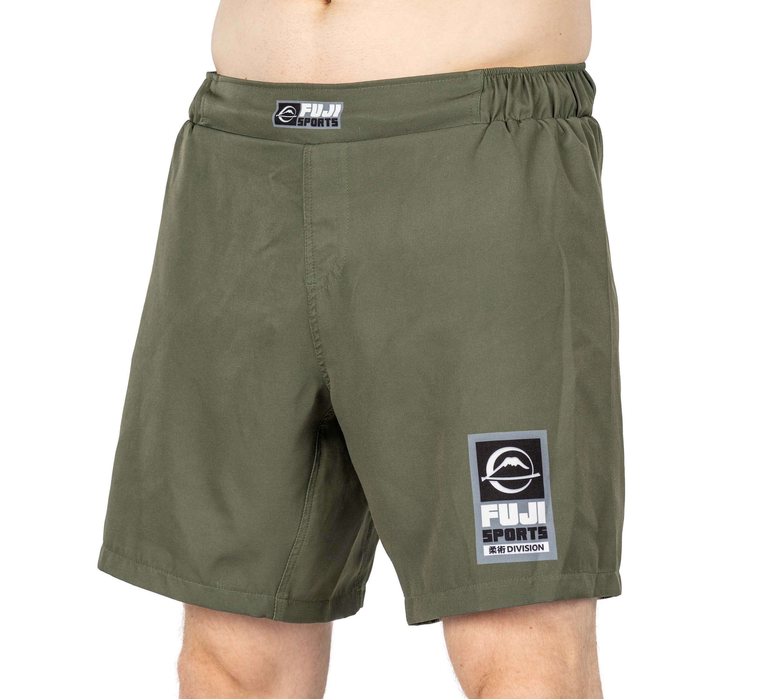 Someone wearing Ultimate Grappling Shorts Military Green with a black and white FUJI patch on the left leg and waistband. Only the lower torso and upper legs are shown.