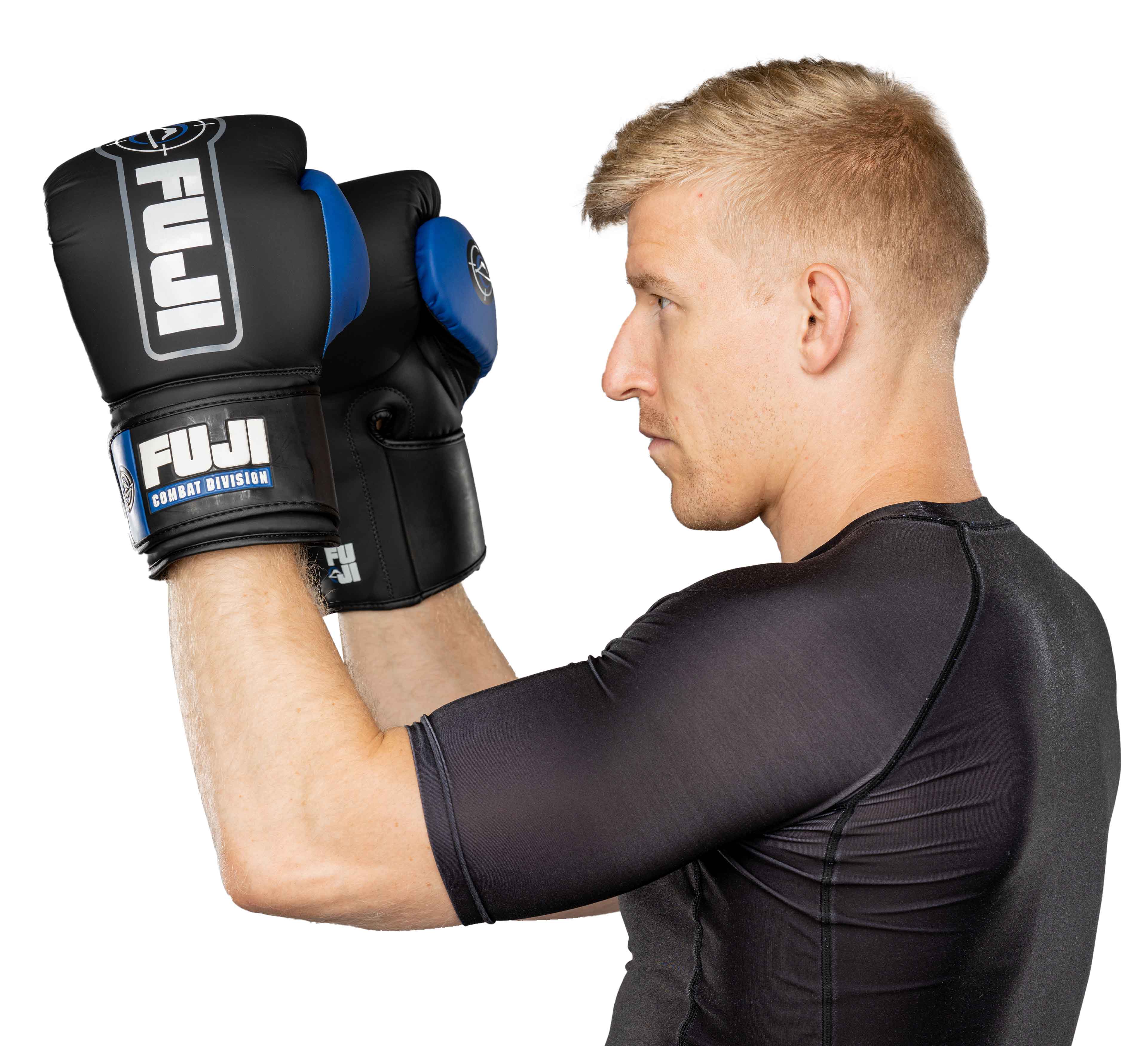 A man wearing blue Precision Boxing Gloves and a black athletic shirt holds his gloved fists up in a defensive stance, viewed from the side against a white background.