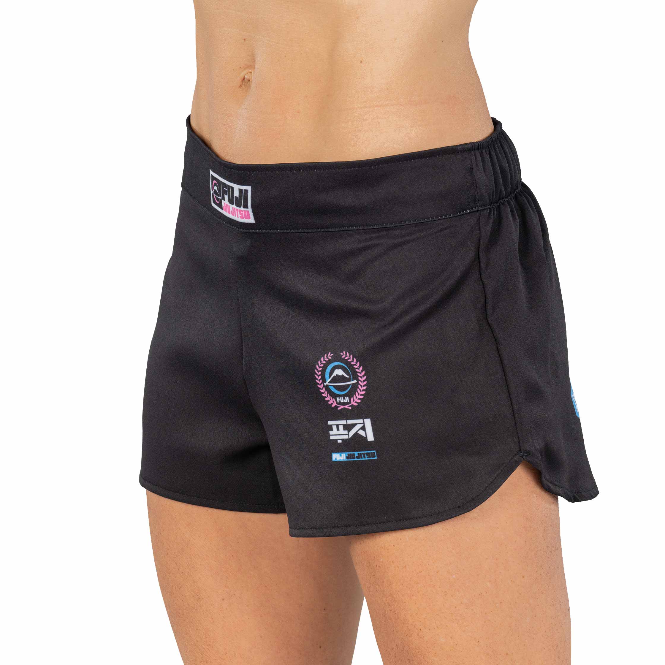 A person is shown from the waist to mid-thigh wearing XTR Extreme Womens Grappling Fight Shorts in pink, featuring logos and text on the front, a side slit, and an elastic waistband.