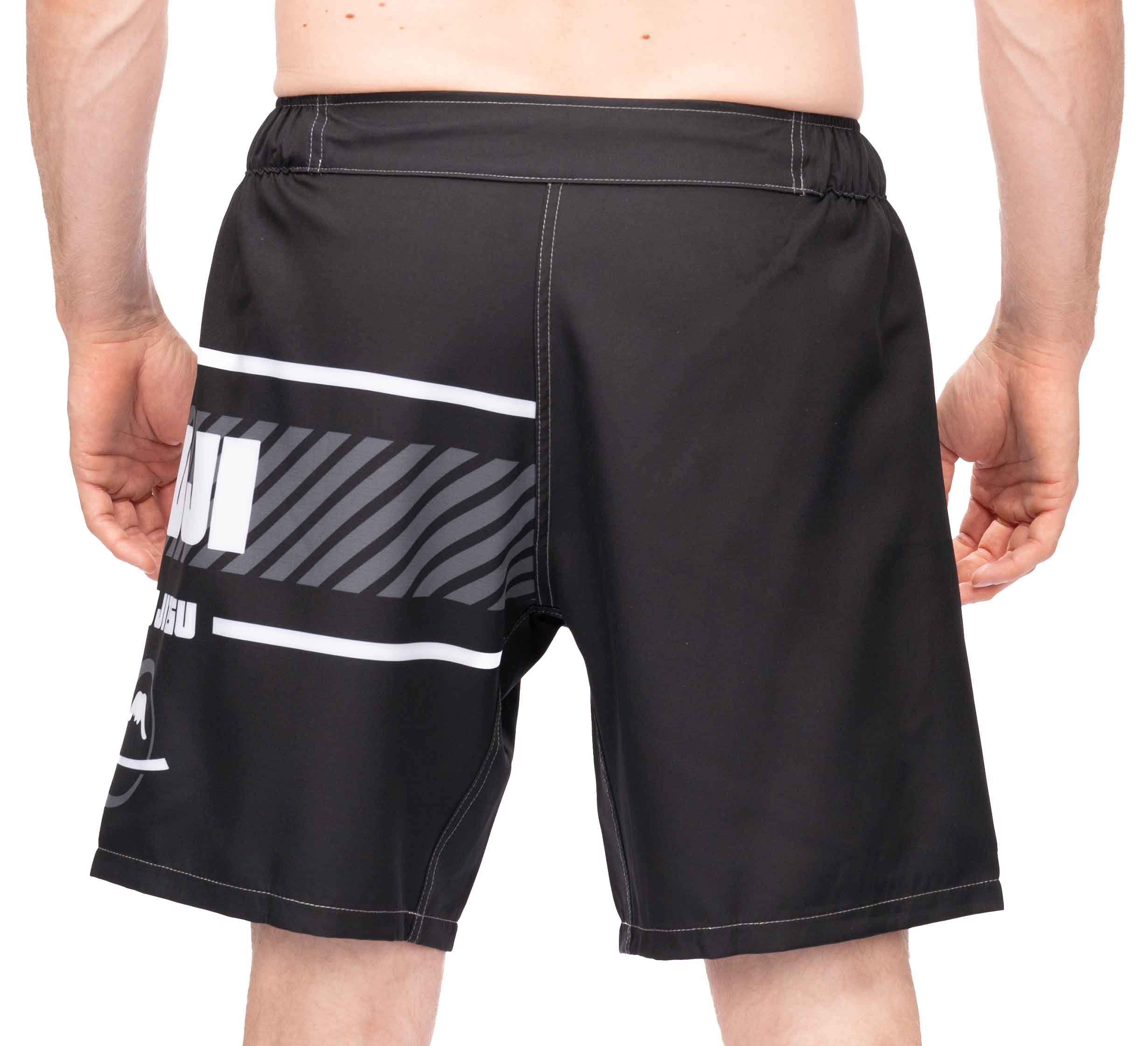 A person is shown from the back wearing Freestyle 2.0 Ranked Grappling Shorts, featuring black fabric with white and gray graphic stripes and text on the left side, plus an elastic waistband.