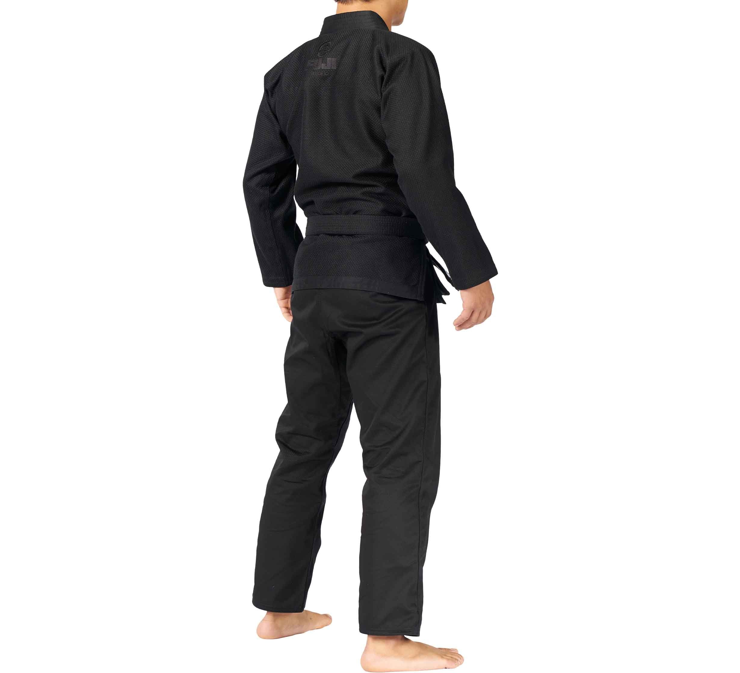 A person wears the All Around BJJ Gi Blackout and belt, standing barefoot on a white background with their back to the camera.