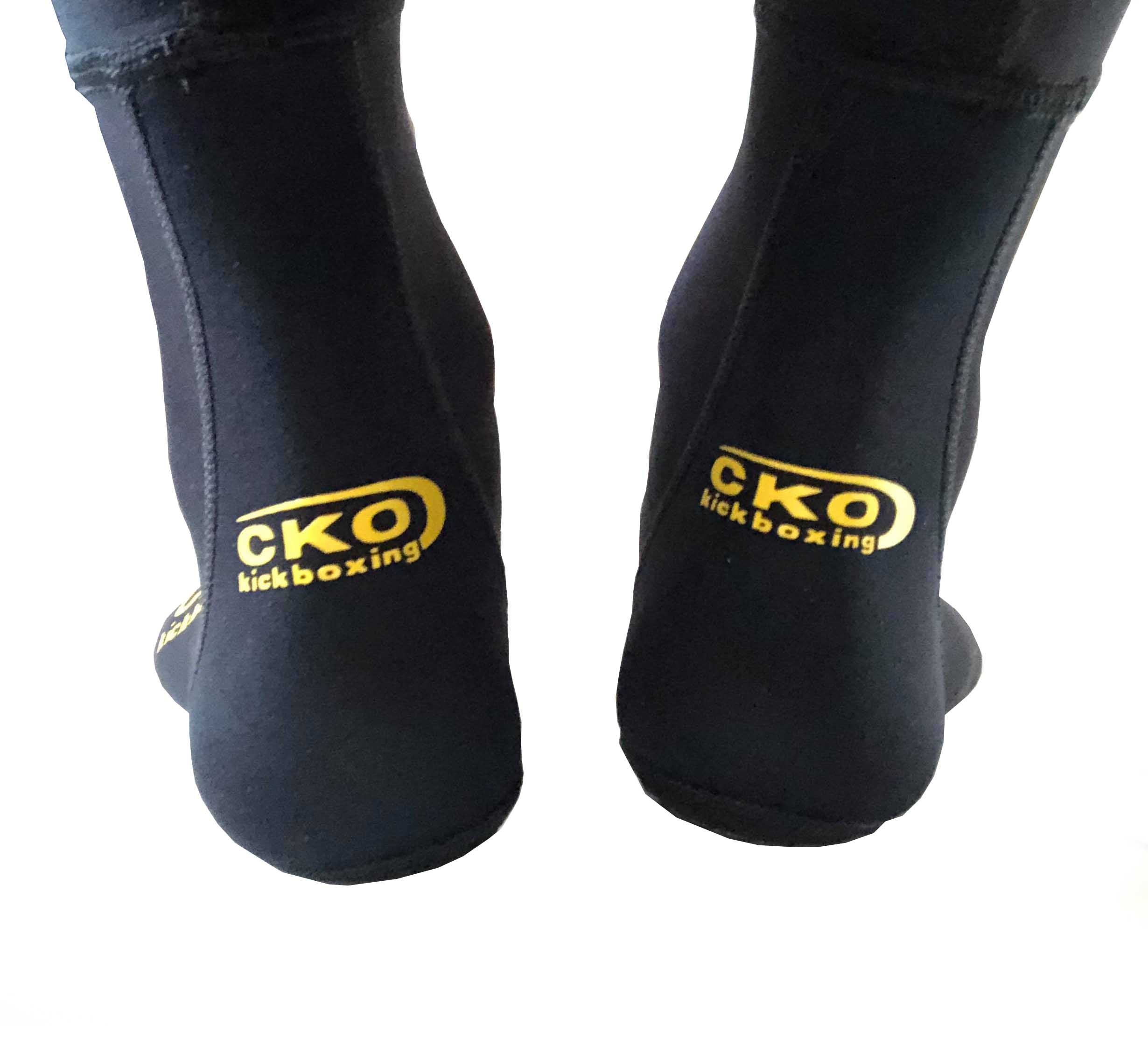A pair of feet wearing black CKO Grip Socks with "CKO Kickboxing" printed in yellow on the back, shown against a white background.
