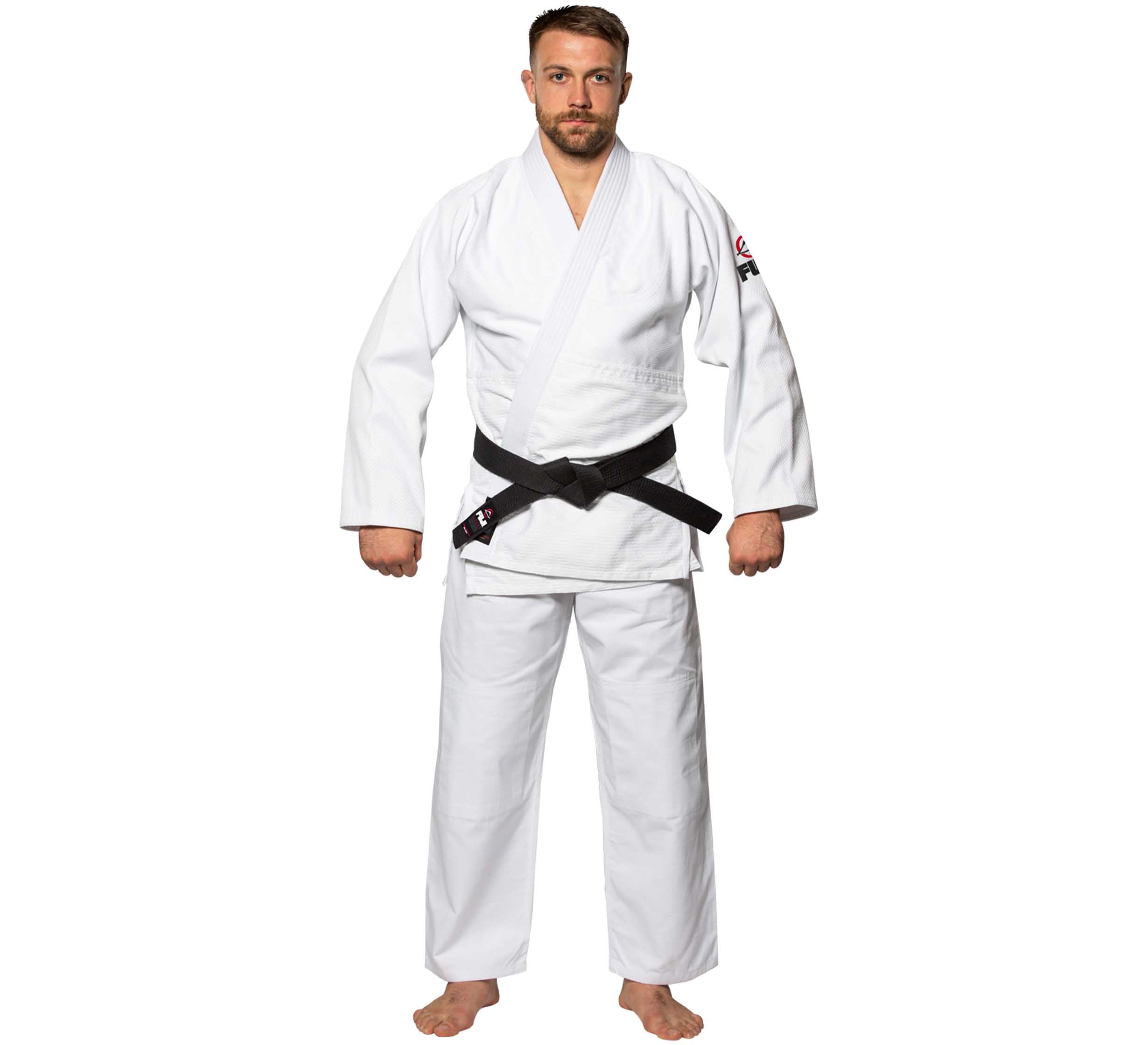 A man stands facing forward in a Single Weave Judo Gi with a black belt, barefoot and neutral-faced, against a white background.