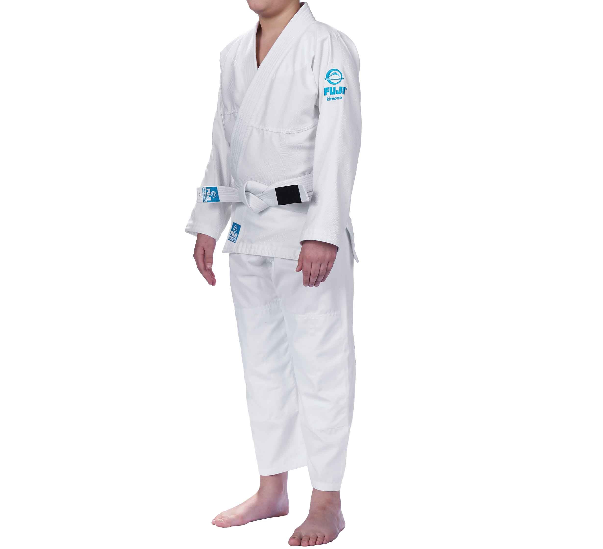 A person stands barefoot, wearing the Starter Kids BJJ Gi White uniform with a white belt and blue Fuji patches, visible from shoulders down against a white background.