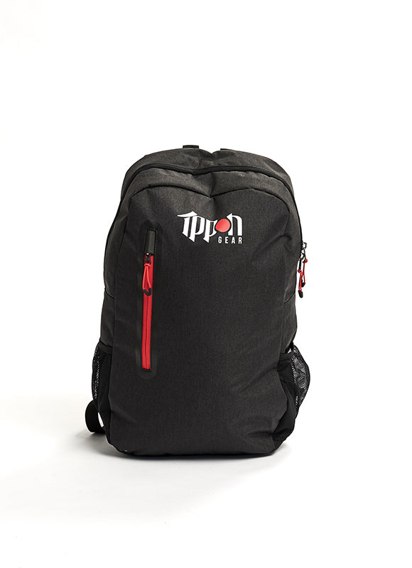 The Ippon Gear Kid's Backpack Fighter is black with a white and red TTPon Gear logo on the front, a red zipper on the front pocket, mesh side pockets, and displayed on a plain white background.