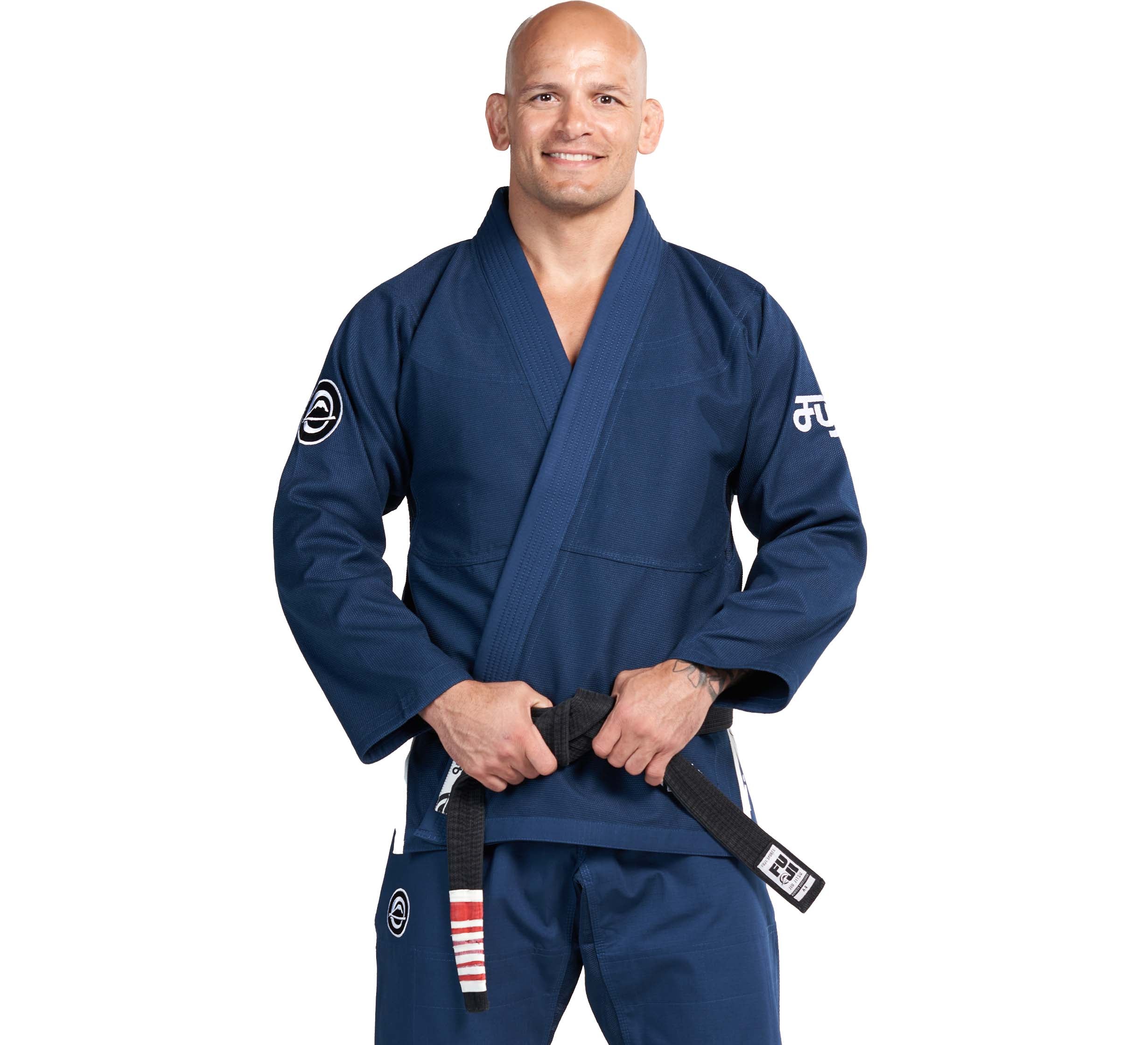 Wearing the Flow-Tech BJJ Gi Navy, a person smiles while holding a black belt with red and white stripes, standing against a plain white background.