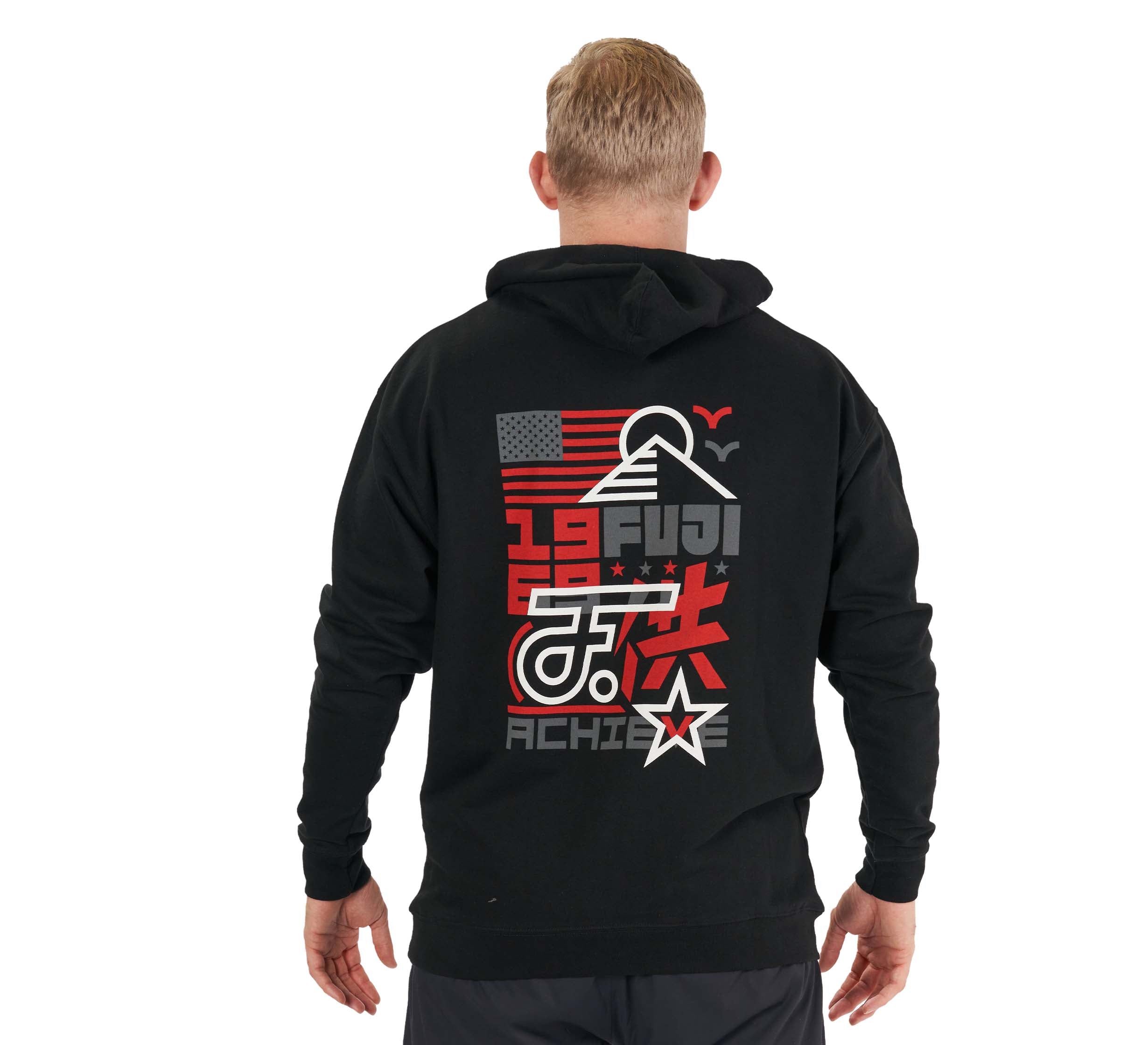A man with short blond hair faces away, wearing the Achieve Hoodie Black, which features bold graphics on the back: FUJI, an American flag, Mount Fuji outline, red Japanese characters, a star, and the word ACHIEVE.