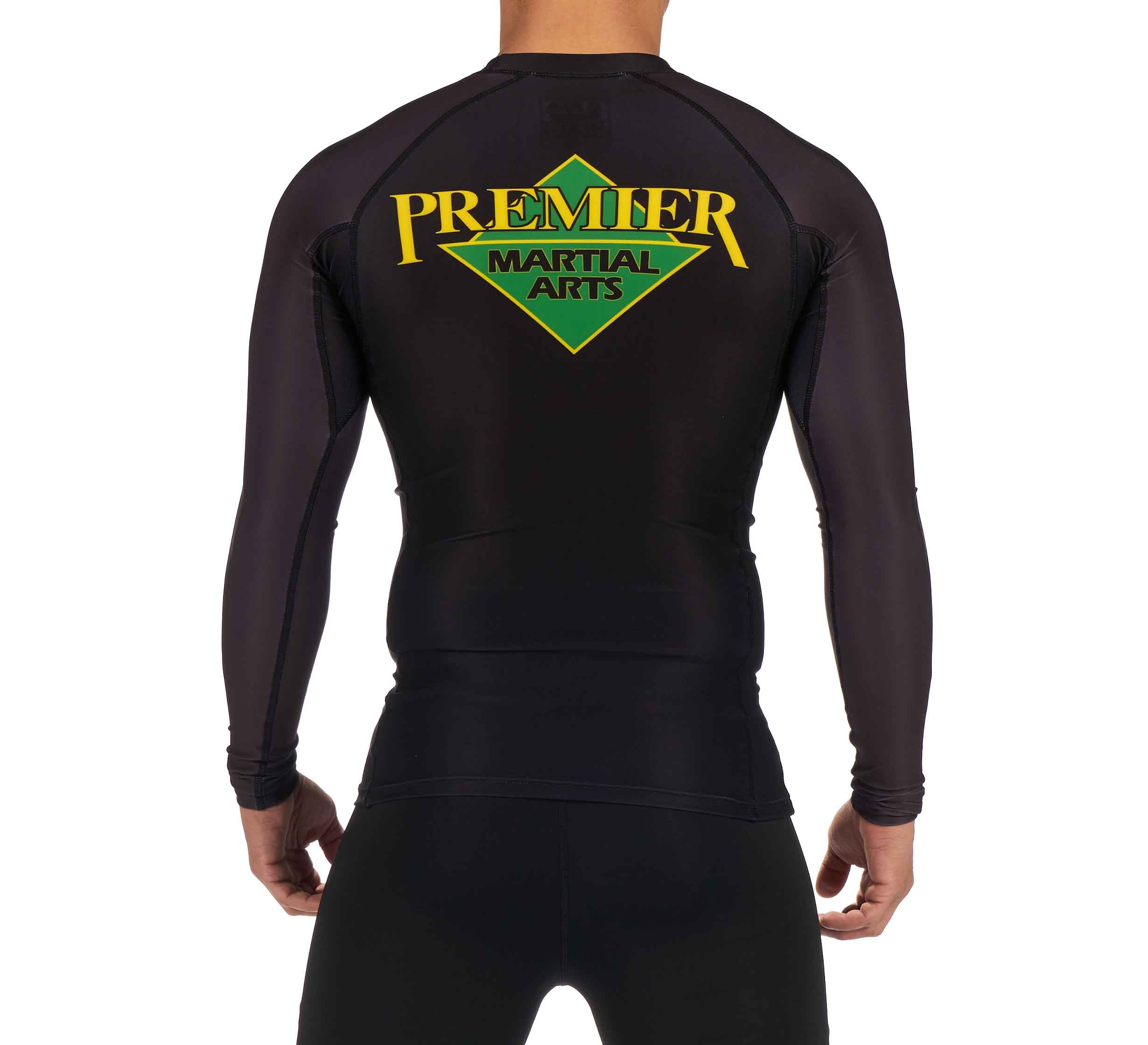 A person is seen from the back wearing the Premier Martial Arts Long Sleeve Rashguard in black, featuring the brand’s yellow and green logo on the upper back.