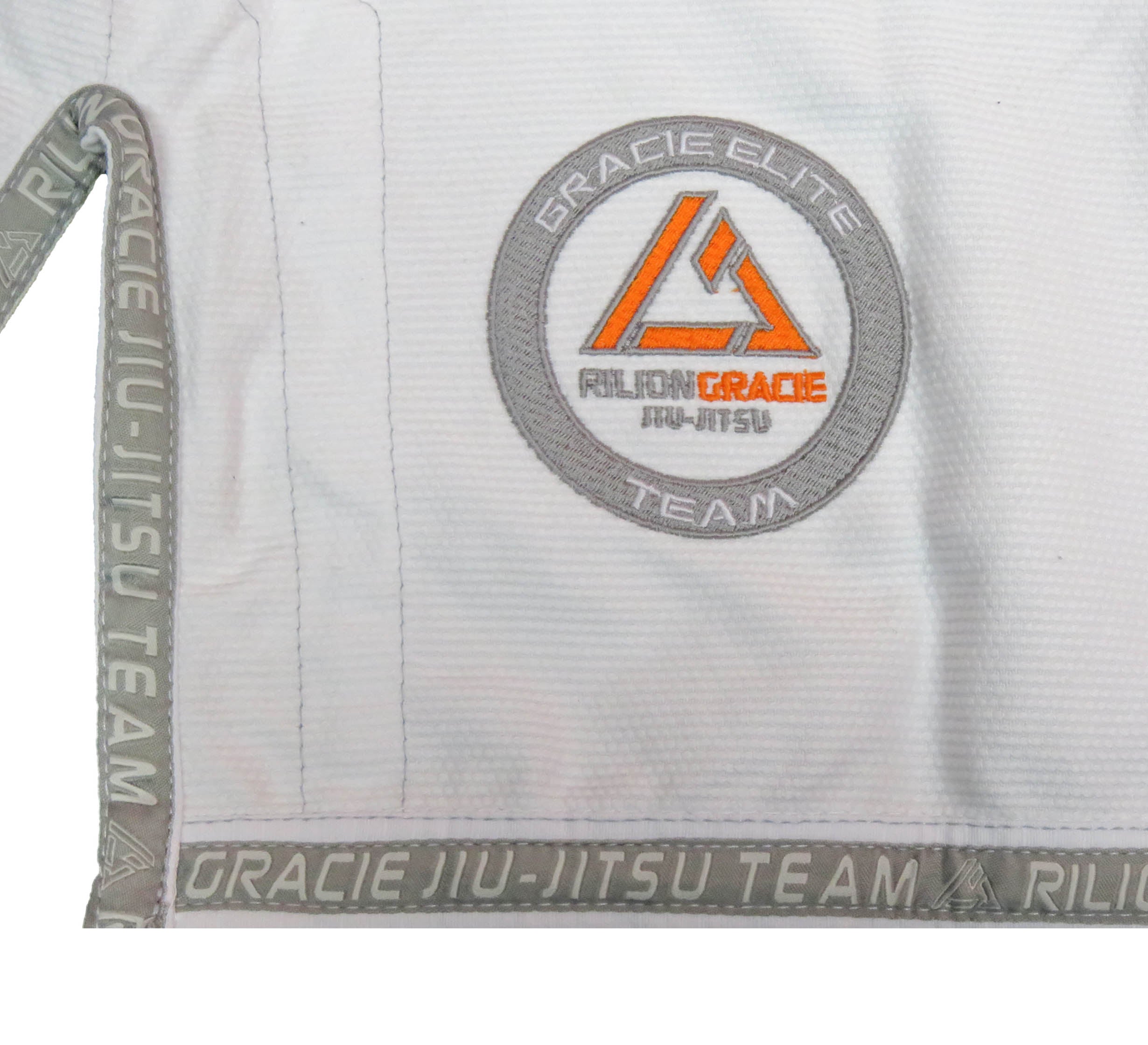 Close-up of the Rilion Gracie Superlite Gi, a white martial arts uniform with grey trim printed with "Gracie Jiu-Jitsu Team" and a patch reading "Gracie Elite Team Rilion Gracie Jiu-Jitsu.