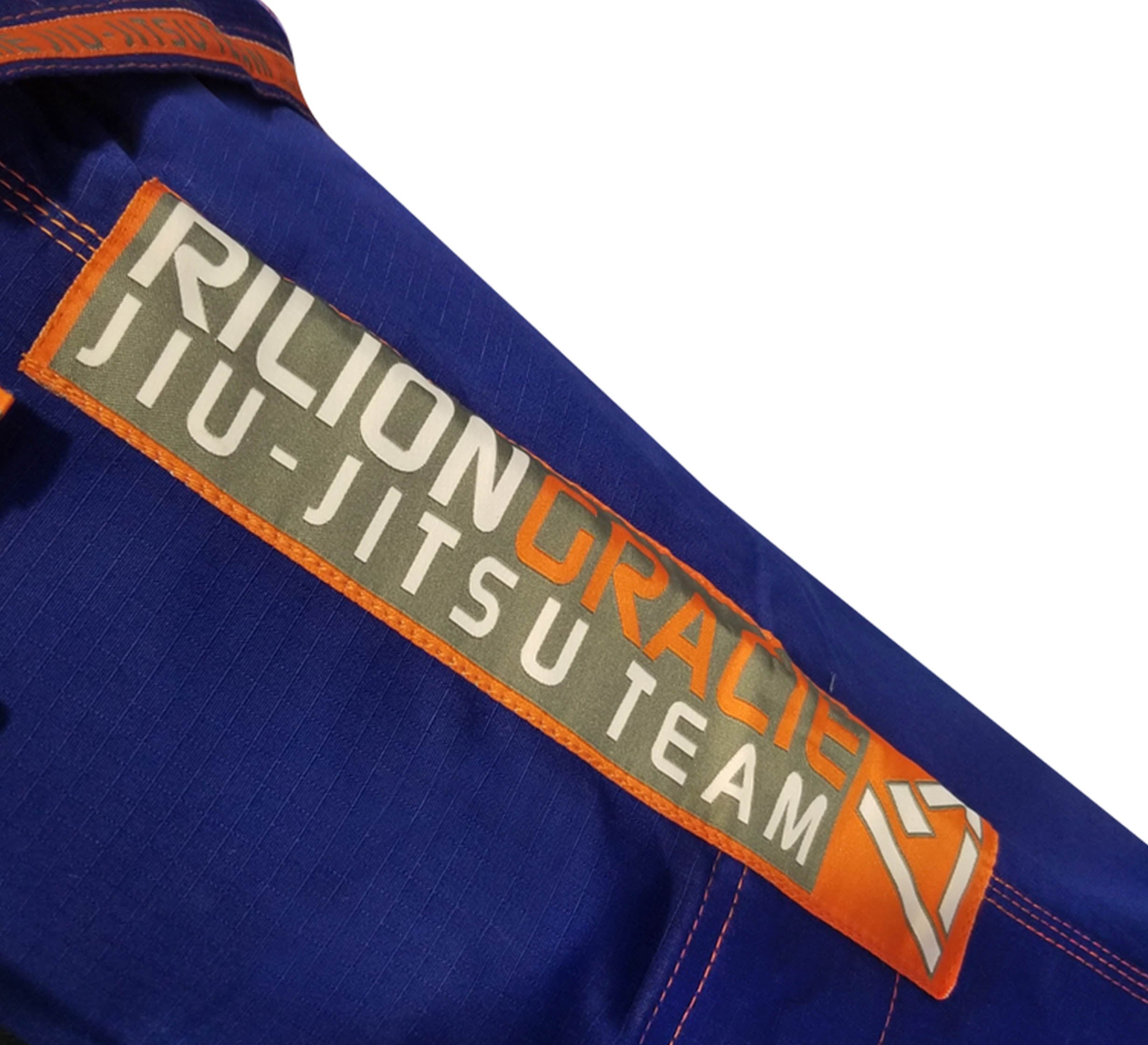A close-up of the Rilion Gracie Superlite Gi in blue, featuring an orange and gray "Rilion Gracie Jiu-Jitsu Team" patch sewn on the sleeve.
