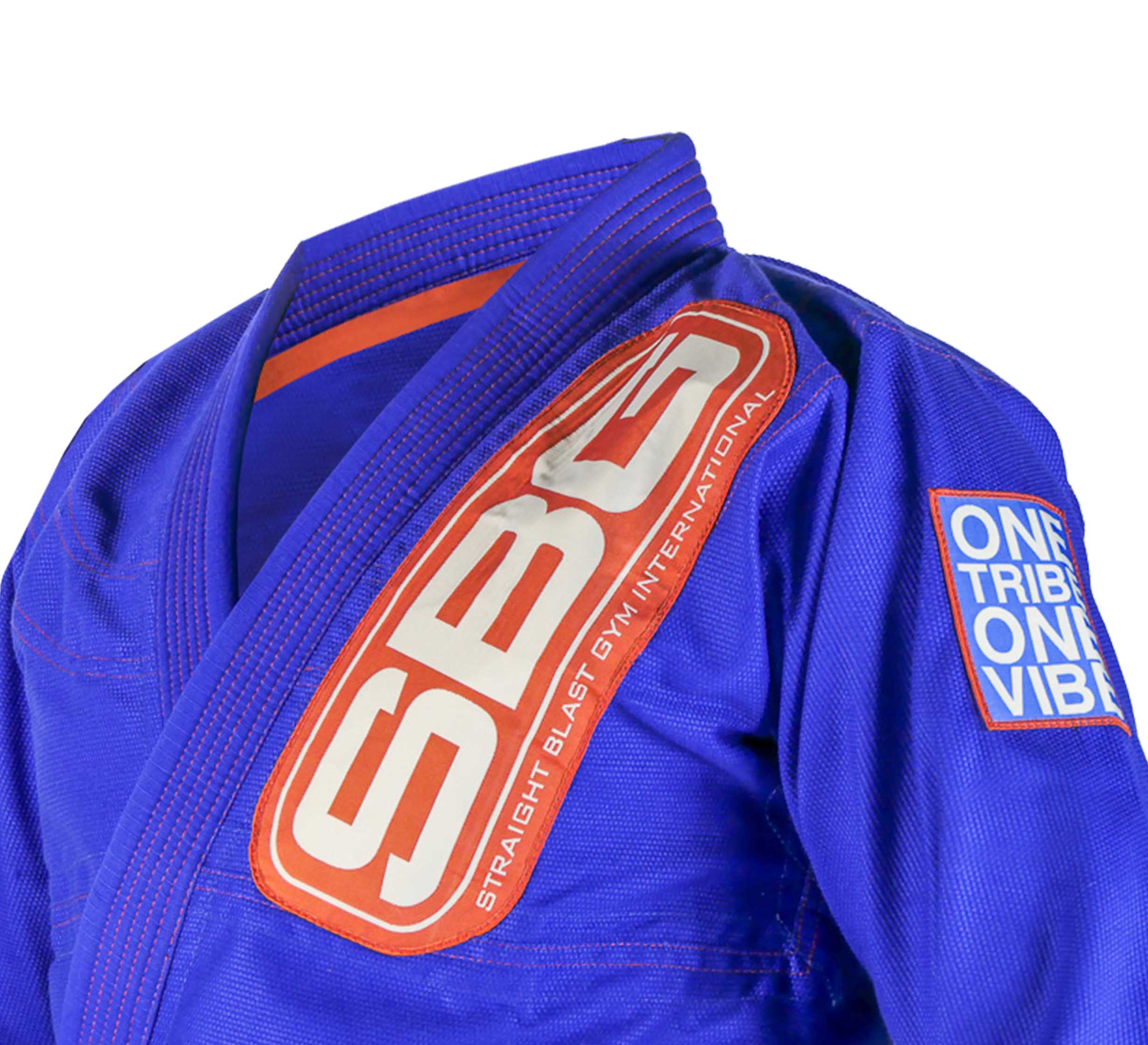 A close-up of the SBG One Tribe Blue Super Lite Womens Gi featuring a red SBG patch on the chest and a blue ONE TRIBE ONE VIBE patch on the sleeve.
