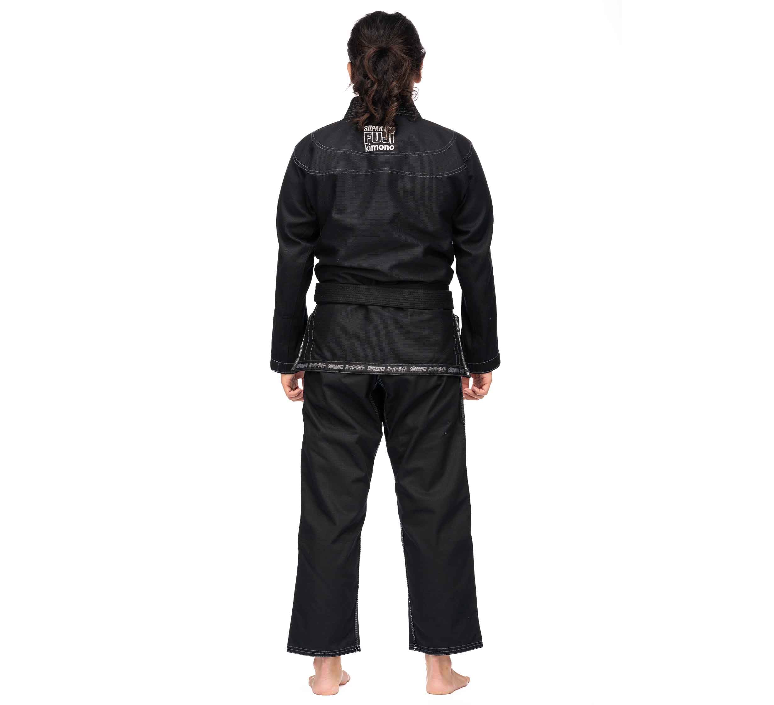A person stands barefoot facing away, wearing the Suparaito BJJ Gi (Unisex Size) in black with a belt and white stitching, against a plain white background.