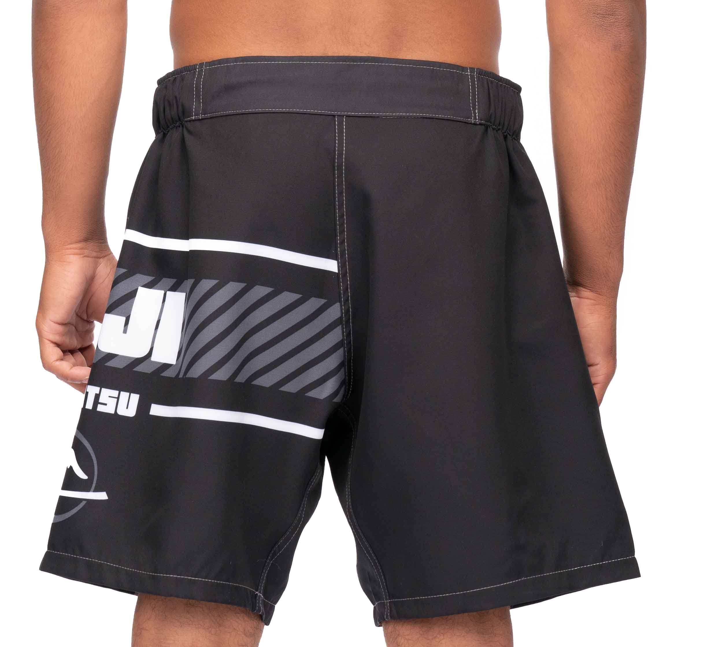 A person shown from the back wears Freestyle 2.0 Ranked Grappling Shorts—black with white and gray graphic text on the left side, featuring an elastic waistband and a loose fit.