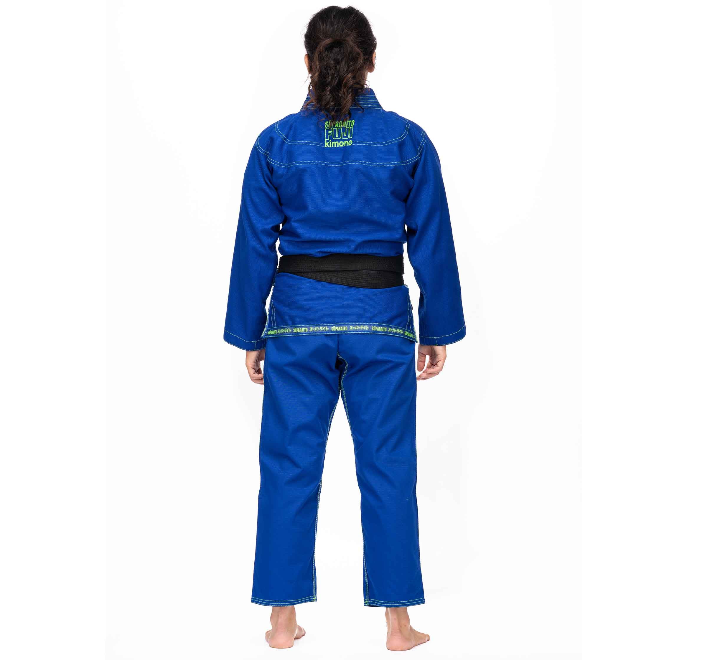 A person with long dark hair, barefoot and facing away from the camera against a white background, is wearing the Suparaito BJJ Gi (Unisex Size) Blue with a black belt.